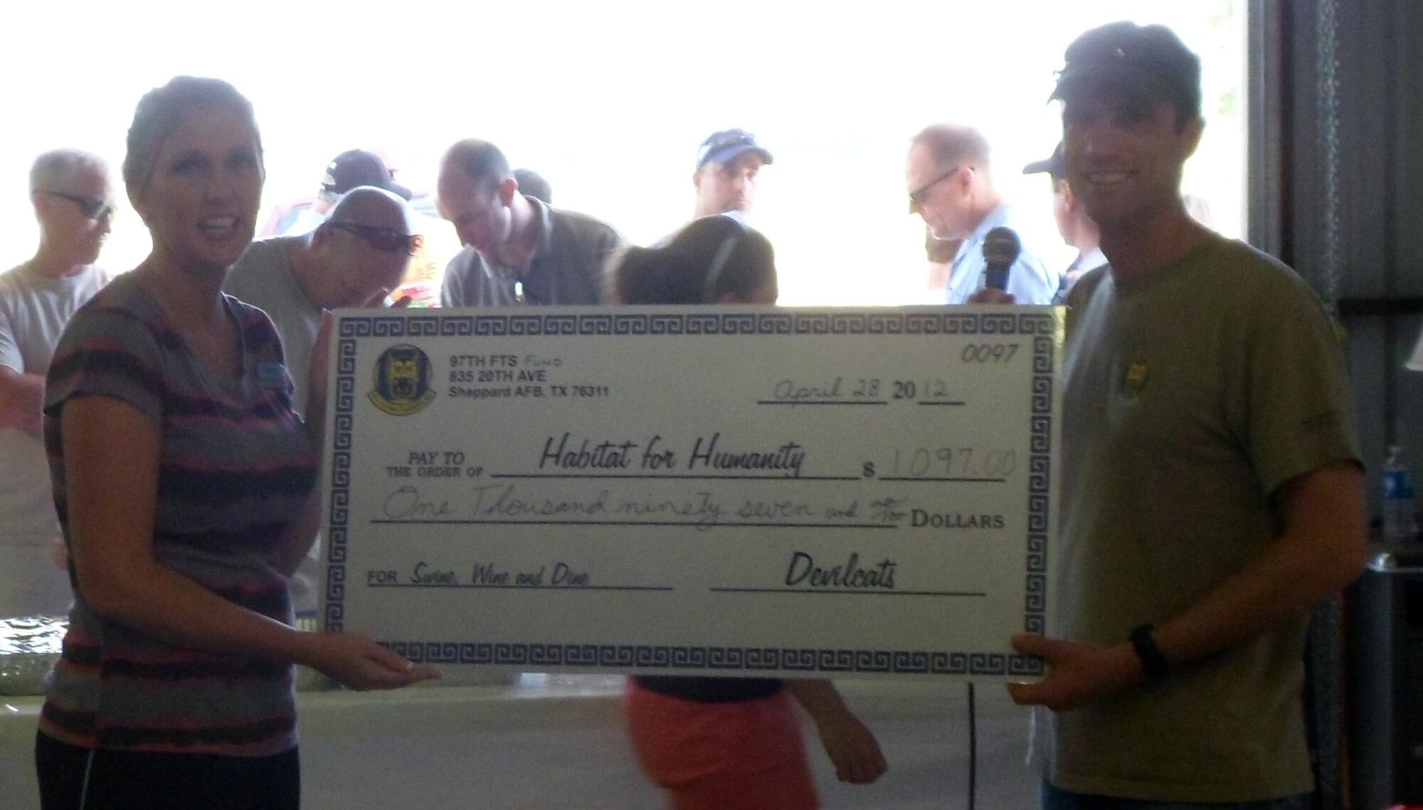 Booster Club President Daniel Scheuermann hands a "big check" to Habitat for Humanity Director of Marketing Lauren Carrell on 28 April 2012.  The 97th Flying Training Wing booster club raised $1,097 for the organization. (97th FTW Courtesy Photo)