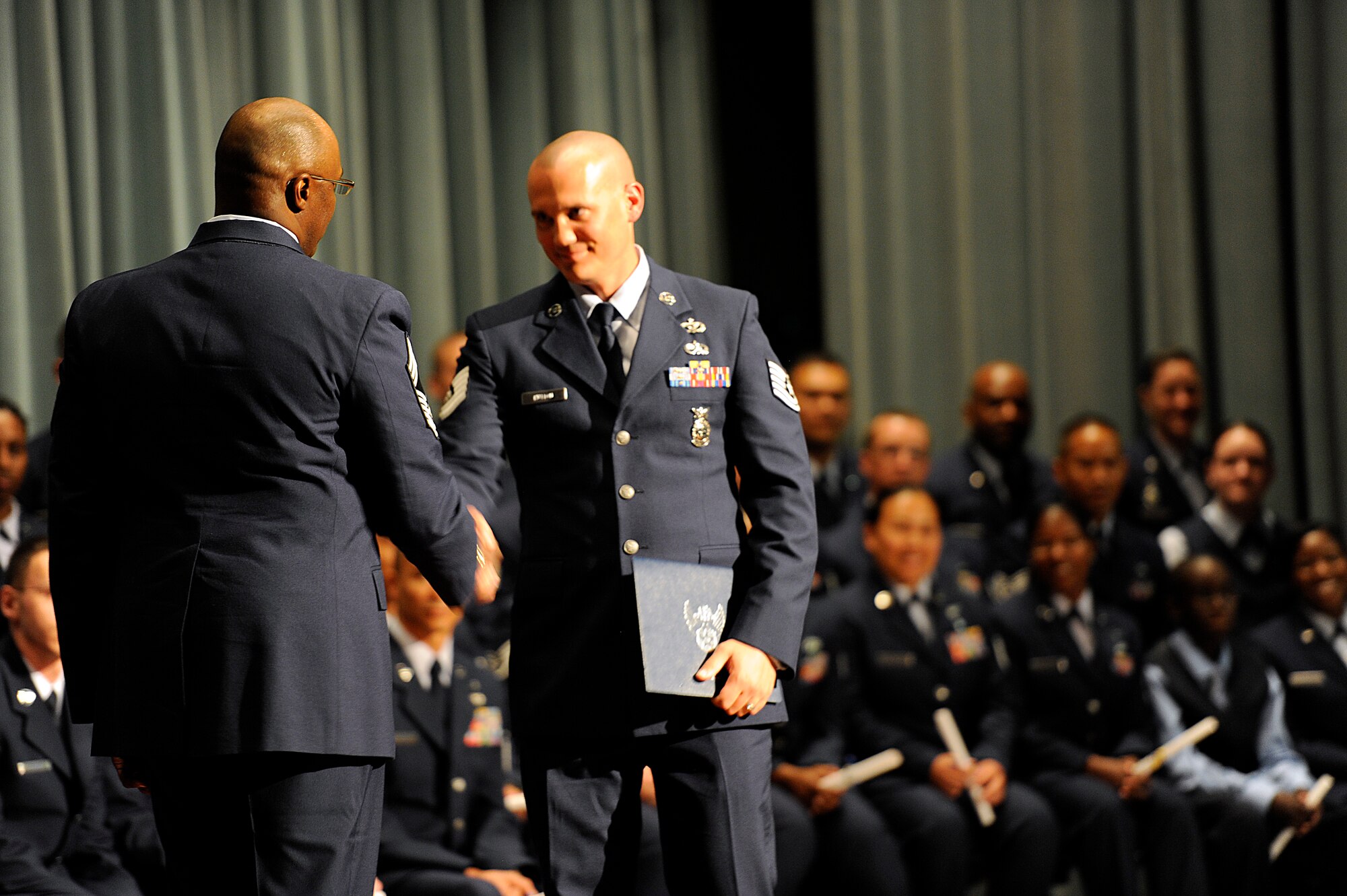 A Community College of the Air Force graduate receives the Aerospace Education Foundation Pitsenbarger Award during the graduation ceremony at the Keystone Theater on Kadena Air Base, Japan, May 24, 2012. The Pitsenbarger Award is a grant endowed to CCAF graduates who plan to pursue a baccalaureate degree. (U.S. Air Force photo/Airman 1st Class Maeson L. Elleman)