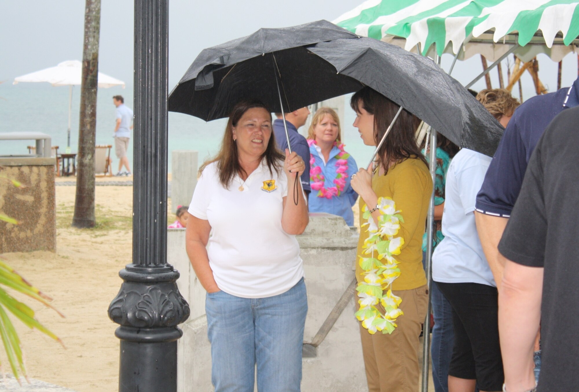 Spouses of deployed military members hold onto their umbrellas to keep the raindrops off of them during a luau held on Torii Station May 19. (U.S. Army photo/Lauren Hall)