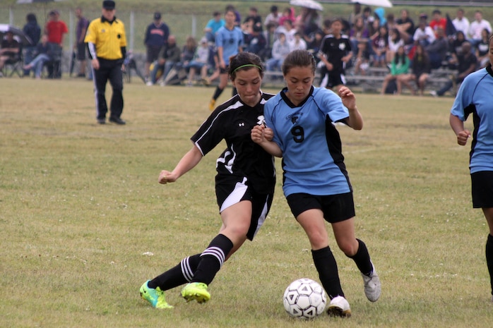 (Left) Sierra Apple, a Matthew C. Perry High School Lady Samurai soccer player fights with an Osan American High School Lady cougar player for control of the ball during the 2012 Division II Far East Soccer Tournament at Penny Lake field here May 25, 2012. The tournament started May 21. The Lady Samurai won the championship 5-2. The Lady Samurai were able to pull away with a series of late scores. This was the Lady Samurai’s first championship and the first time both the girls’ and boys’ soccer teams have won championships simultaneously, with the Samurai beating the Yongsan International School of Seoul Guardians at Osan 4-2.