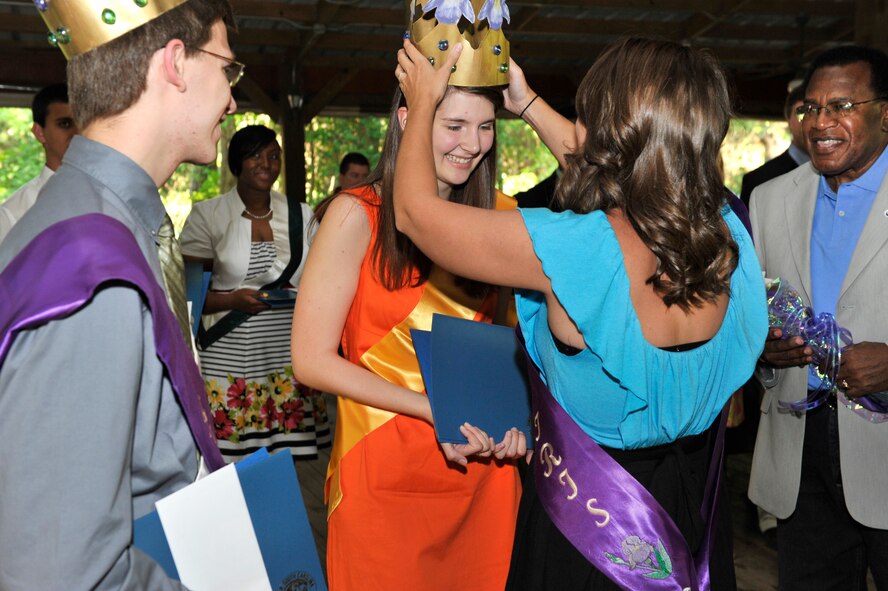 Nicholas Lavergne , King of the Iris from St. Francis Xavier High School, and Eugene Baten, Sumter County Council chairman, watch as Catherine Foley, a Sumter High School student, gets crowned Queen of the Iris by former Queen of the Iris Lindsey Cox, Sumter, S.C., May 24, 2012. The official ribbon cutting ceremony kicked off the three day Iris Festival at Swan Lake Iris Gardens. (U.S. Air Force photo by Senior Airman Amber E. N. Jacobs/Released)
