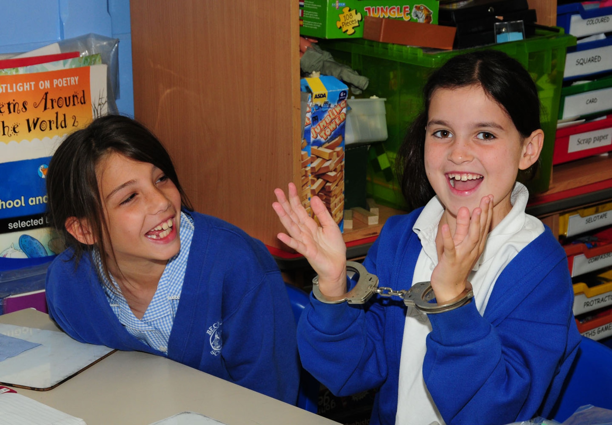 BECK ROW, England – Eden Handy, right, 9, tries on some handcuffs as her classmate, Natalie Harrison, 9, looks on May 25, 2012, at Beck Row Primary School near RAF Mildenhall. Seven members from the 100th Security Forces Squadron visited and talked about their job and what they do to protect people. They also brought various items for the children to look at, including night-vision goggles, a Kevlar helmet and bandages. (U.S. Air Force photo/Karen Abeyasekere)