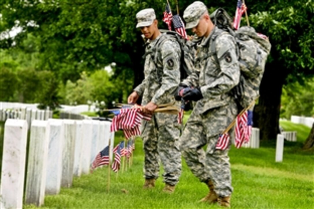 Army Pvt. Aaron Johnson places a small American flag in front of a grave during the annual "Flags In" event to commemorate Memorial Day at Arlington National Cemetery in Arlington, Va., May 24, 2012. Johnson, assigned to the Army's 3rd U.S. Infantry Regiment, "The Old Guard," was one of several soldiers to place flags in front of more than 260,000 gravestones and about 7,300 niches at the cemetery's columbarium. 