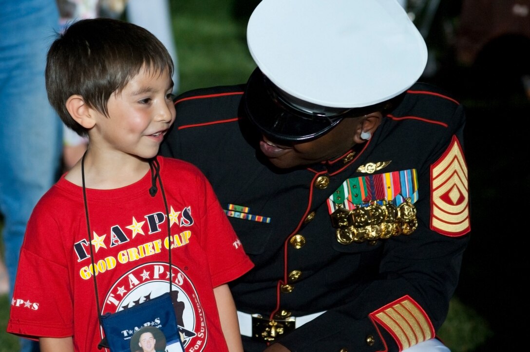 1st Sgt. Charles Peoples, Guard Company first sergeant, laughs with a Tragedy Assistance Program for Survivors child following a Friday Evening Parade at Marine Barracks Washington May 25. TAPS supporters and members sat in prime, front row seats while they enjoyed the parade. TAPS is a national, non-profit organization made up of, and providing services to, all those who have lost a loved one on active duty with the Armed Forces.