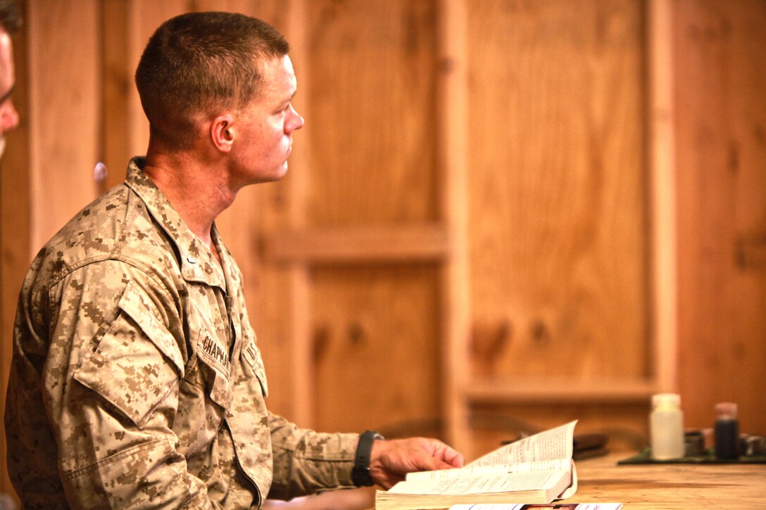1st Lt. Rick Chapman, executive officer for Police Advisory Team, 2nd Battalion, 5th Marine Regiment, listens to Navy Cmdr. Francis Foley, the command chaplain for 3rd Marine Aircraft Wing (Forward), during a Catholic Mass service at Combat Outpost Now Zad, Afghanistan, May 27. Religious personnel from 3rd Marine Aircraft Wing (Forward) flew to the outpost to attend to the spiritual needs and to deliver care packages.