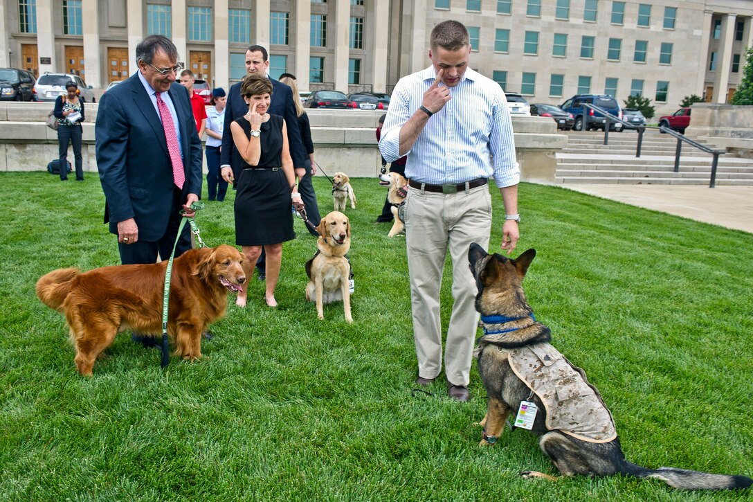 Defense Secretary Leon E. Panetta and his dog, Bravo, watch as Navy Corpsman Marshall Peters gives his dog, Sgt. Archie, hand signals during a meeting at the Pentagon, May 23, 2012. Peters and Archie are members of the Warrior Transition Brigade Service Dog Training Program which was created to meet the needs of service members and veterans with psychological and physical injuries.