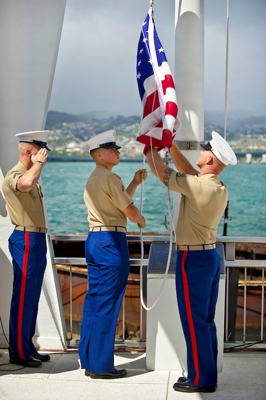 Marine Corps Cpl. Brandon Riles, right, salutes as Marine Corps Pfc. Travis Gorbey and Marine Corps Staff Sgt. Steve Snell raise the U.S. flag during the USS Arizona Memorial 50th anniversary commemoration ceremony at the USS Arizona Memorial in Honolulu, Hawaii, May 27, 2012.