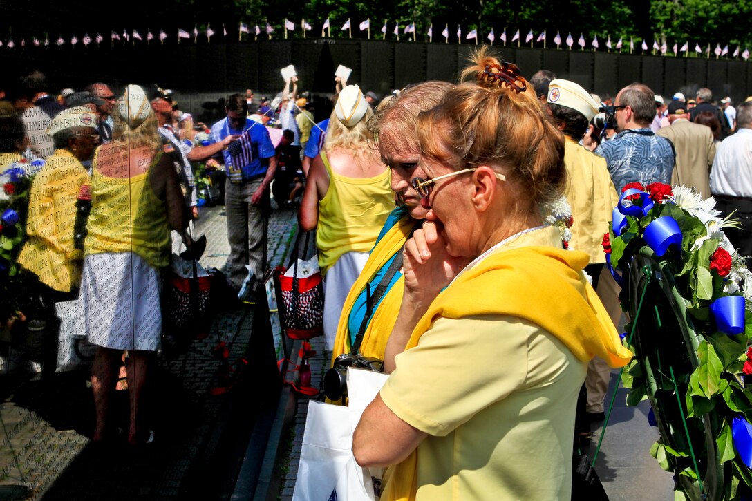 Kathy Cardona and her daughter, Julianna Blamire, both of Connecticut, hold back emotion as they look at the name of Cardona's husband, Army Staff Sgt. Ronald Cardona, on the Vietnam Veterans Memorial in Washingtin, D.C., after attending a ceremony at the wall to commemorate the 50th anniversary of the Vietnam War. Cardona said her husband was a Ranger and loved serving as one.