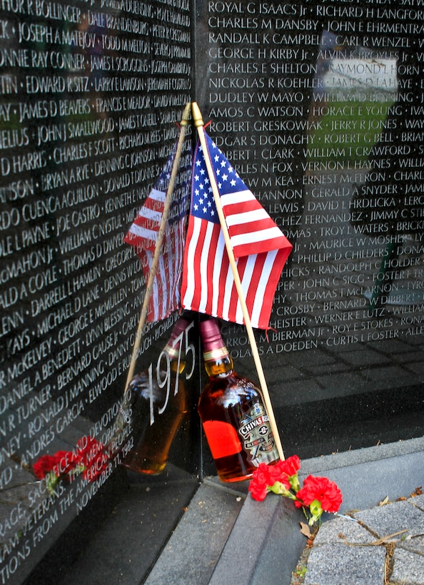 An American flag, a flower and a bottle of Scotch lean against the Vietnam Veterans Memorial after a ceremony marking the 50th anniversary of the Vietnam War at the memorial wall in Washington, D.C., May 28, 2012.