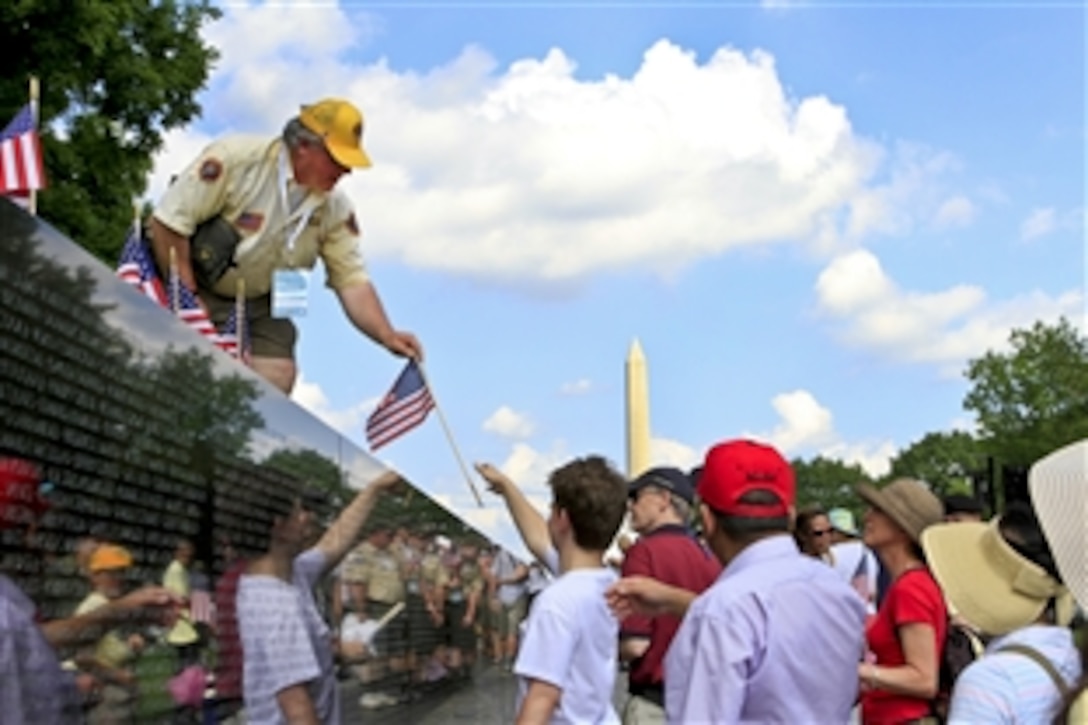 Allen McCabe, a volunteer for the Memorial Day event commemorating the 50th anniversary of the Vietnam War, hands out American flags that lined the top of the Vietnam Veterans Memorial in Washington, D.C., May 28, 2012.