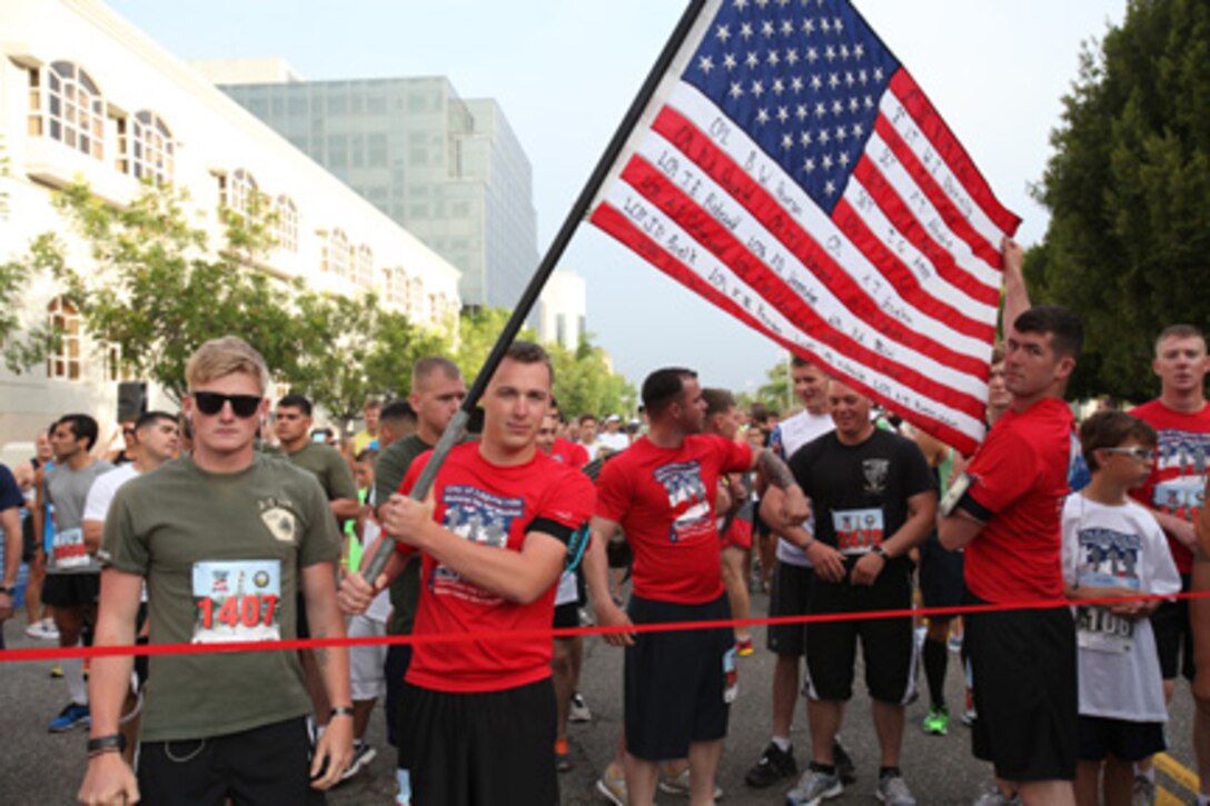 Marines from Battalion Landing Team, 3rd Battalion, 5th Marines, 15th Marine Expeditionary Unit, Camp Pendleton, Calif., carry an American Flag bearing the names of Marines from the unit who have made the ultimate sacrfice in the Laguna Hills Memorial Day Half Marathon in Laguna Hills, Calif., May 28.  More than 100 Marines from the battalion ran in the race in honor of their Marine brothers who lost their lives in battle.  The city of Laguna Hills adopted the battalion in 2007 and have supported it both at home and while deployed.