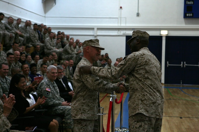 After a final speech and farewell to military leaders and members of the local U.S. Army Garrison Stuttgart community, that he has gotten to know during his two-year tenure as sergeant major of both U.S. Marine Corps Forces Europe and Marine Corps Forces Africa, Sgt. Maj. Ronald L. Green, outgoing sergeant major, welcomes Sgt. Maj. James J. McCook, the incoming sergeant major, as the witnesses to the relief-and-appointment ceremony erupt in applause.  The two commands welcomed their new senior enlisted leader, McCook, as they bid farewell to Green during a relief-and-appointment ceremony, here, May 29.::r::::n::::r::::n::