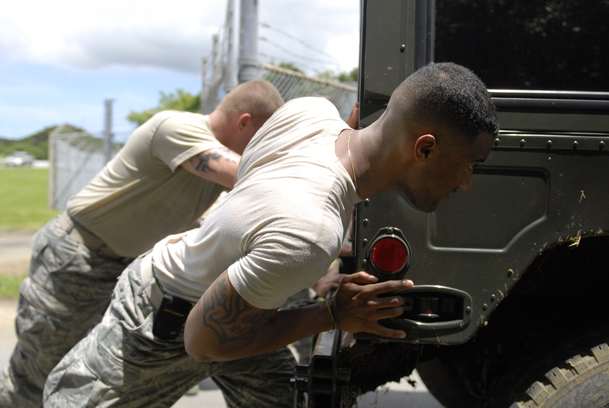 Airman 1st Class Kenneth Stuart and Airman 1st Class Rashawn Richards, 18th Security Forces Squadron Team Charlie, push a Humvee as part of the defenders challenge on Kadena Air Base, Japan, May 22, 2012. Pushing the Humvee not only showcased deployment training, but it also demonstrated the team’s strength and determination to get the job done. (U.S Air Force photo/Airman 1st Class Malia Jenkins)  