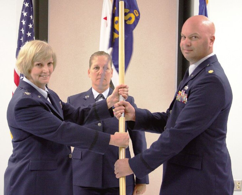 Col. Pamela LeBlanc passes the 56th Aerial Port Squadron flag to Maj. Sean Bathrick, who takes command of the 56th Aerial Port Squadron, at a May 5 ceremony, while Senior Master Sgt. Tina Dunneback, 56th APS first sergeant looks on. (U.S. Air Force photo by MSgt Carson Hampton)