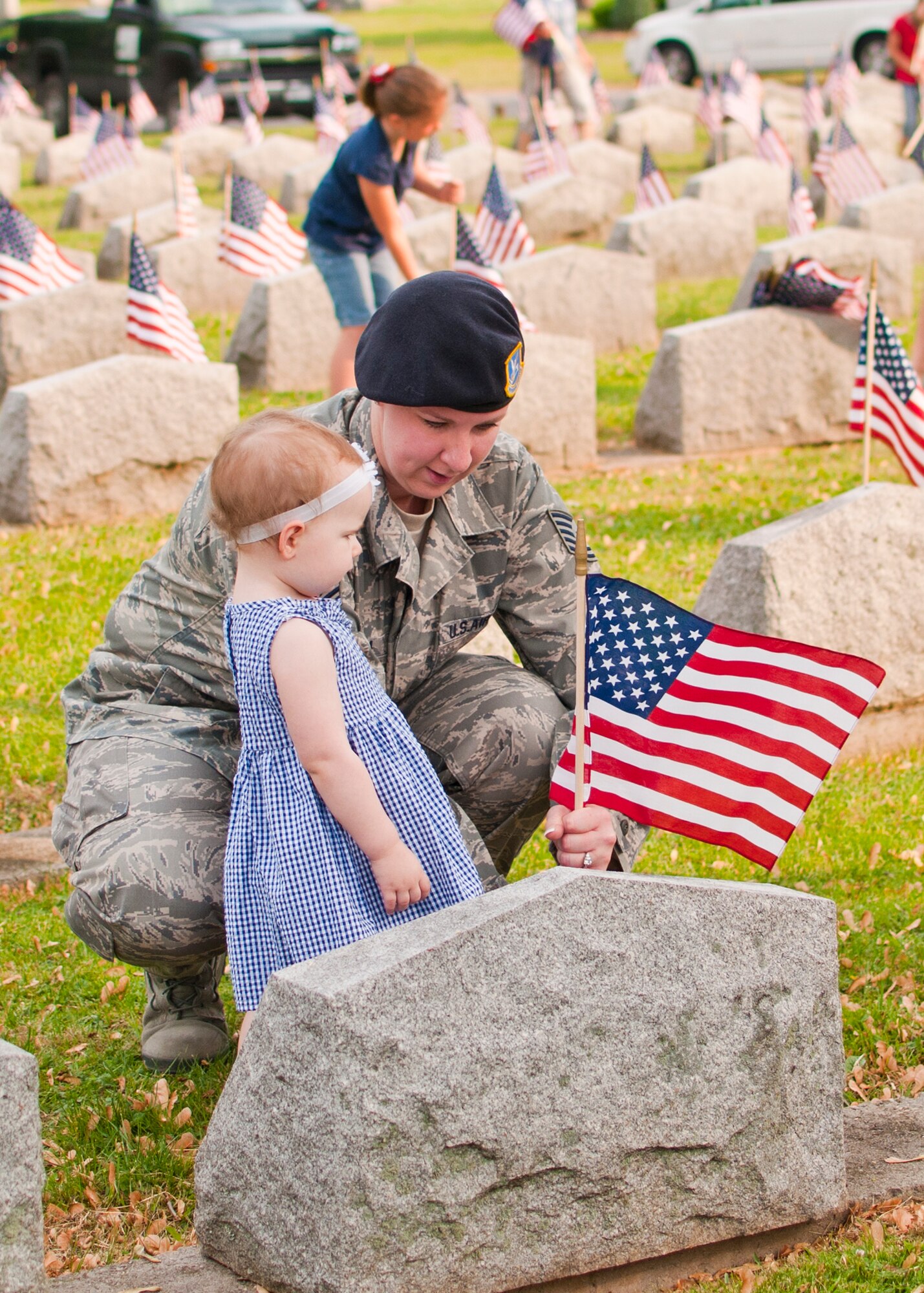 914th Security Forces Tech. Sgt. Cathleen Kania her daughter Kylie place American flags on veteran’s graves during a Memorial Day ceremony, May 28, 2012, Forest Lawn Cemetery Buffalo NY. During the morning thousands of flags where placed next to those men and woman who served in the United States military. (U.S. Air Force photo by Tech. Sgt. Joseph McKee)