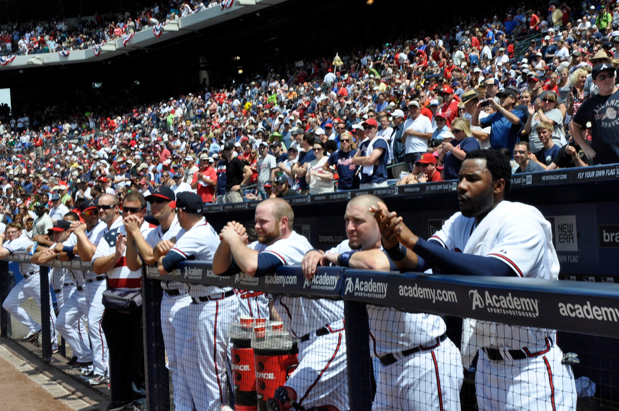 Members of the Braves baseball team applaud with the crowd as Master Sgt. David Sims reunites with his family. Sims returned from a six-month deployment from Kabul, Afghanistan, on May 27 and surprised his family on the field during the 5th inning of the May 28 game. Sims is assigned to Headquarters Air Force Reserve Command’s Communications Directorate at Robins Air Force Base, Ga. (Defense photo/Jessica Blanton)