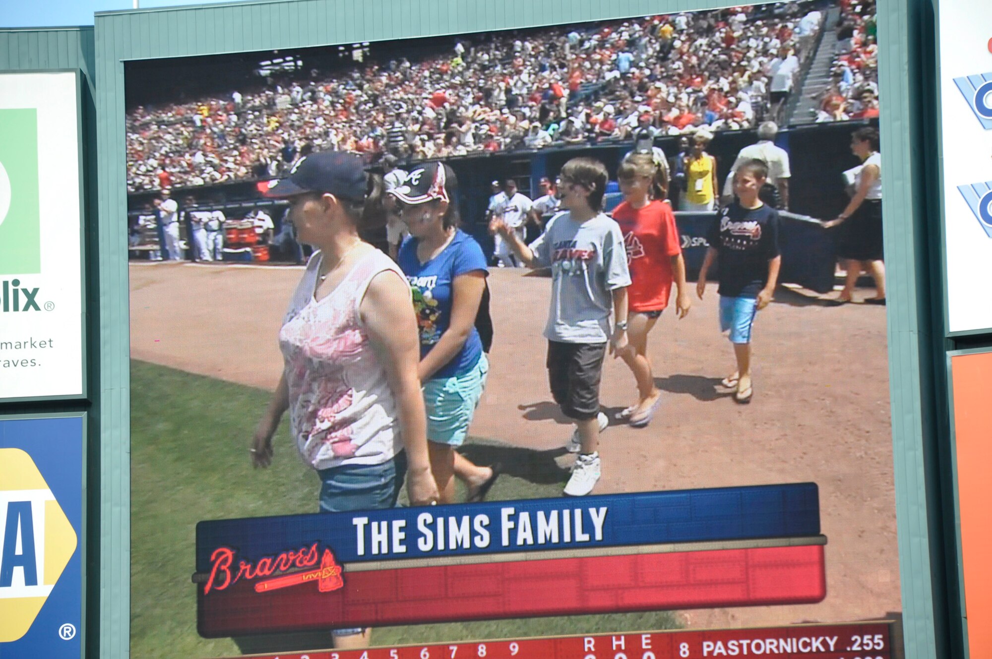 Master Sgt. David Sims' wife and children are featured on the big screen as the Braves Hometown Heroes, representing all military families with loved ones serving overseas. His wife Robin and children BreAnna, Brittany, Dustin, and Roman were moments away from the big surprise, as Sims was hiding on the other side of the dugout. (Defense photo/Jessica Blanton)