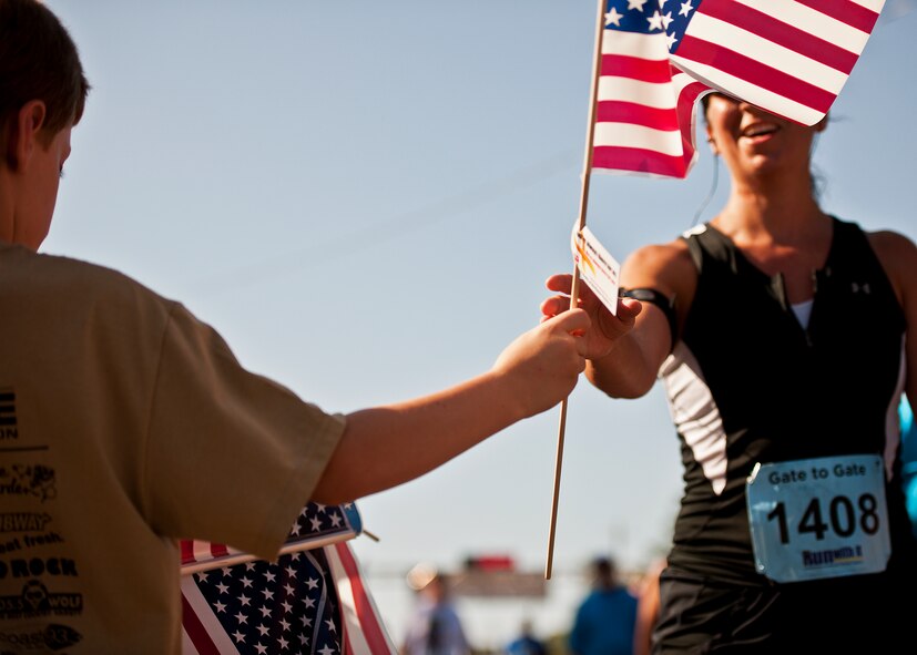 A runner accepts a flag from a volunteer after completing the Gate-to-Gate run May 28 at Eglin Air Force Base, Fla.  More than 1,600 people ran in the annual Memorial Day event.  (U.S. Air Force photo/Samuel King Jr.)