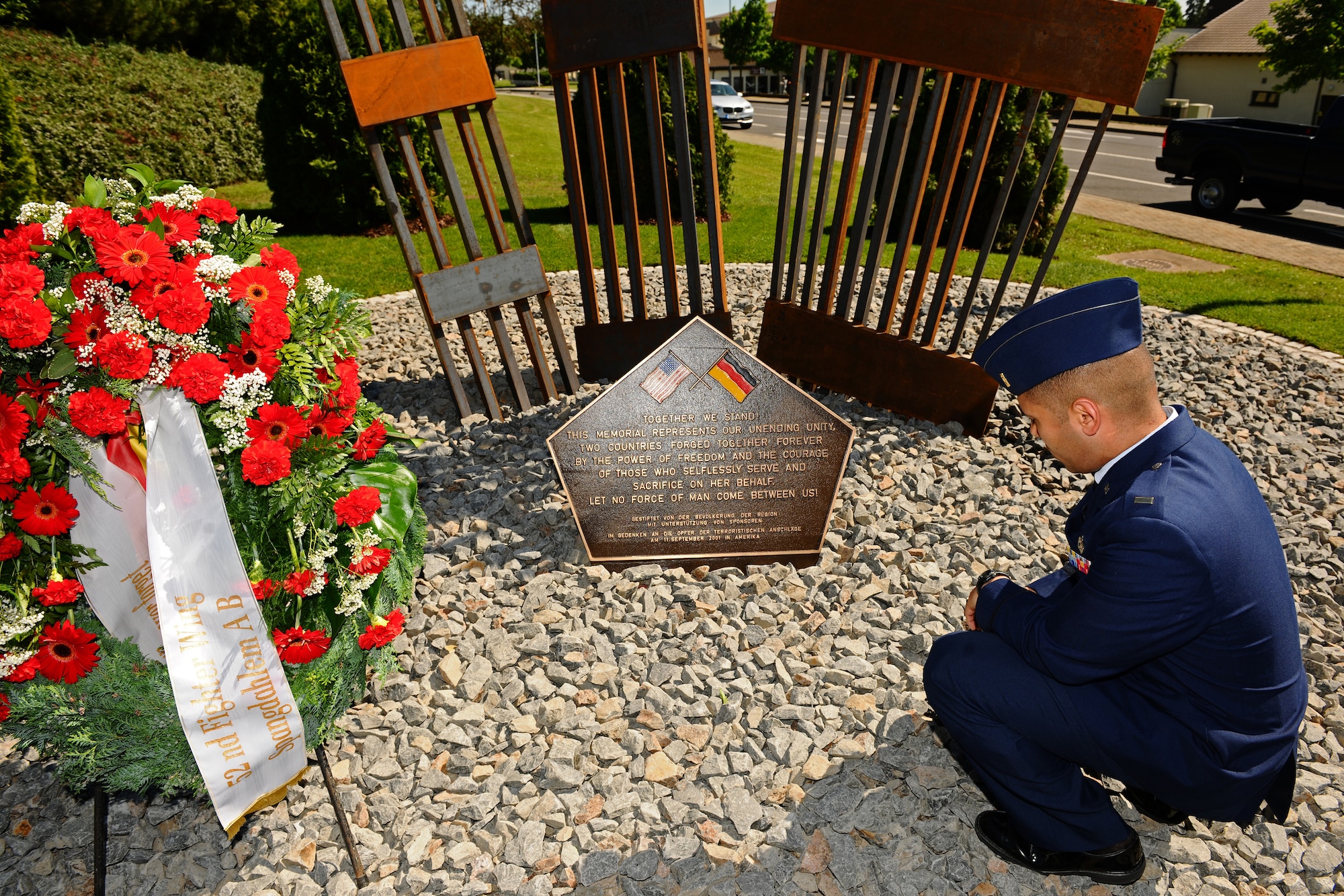 SPANGDAHLEM AIR BASE, Germany – 2nd Lt. Jeffrey Rodriguez, 81st Aircraft Maintenance Unit assistant officer in charge, kneels to pay respect to those who died in the 9/11 attacks after the memorial dedication ceremony here May 25. The 9/11 memorial was donated to the 52nd Fighter Wing by the Host Nation Council Spangdahlem and local businesses.  The sculpture was designed by Hubert Kruft, artist, from Niederpruem. (U.S. Air Force photo by Airman 1st Class Matthew B. Fredericks/Released)