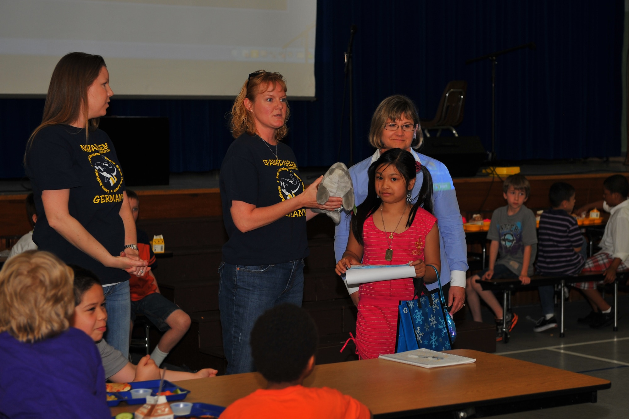 SPANGDAHLEM AIR BASE, Germany – Amy Finley, left, Spangdahlem Elementary School Parent Teacher Student Association president, presents a stuffed dolphin to Danielle Ancheta, third grade student and daughter of Tech. Sgt. Ryan Ancheta, and classmates in recognition of Ancheta’s first-place article during the initial presentation of Delfina’s adoption certificate inside the SES cafeteria here May 25. Delfina is a wild bottlenose dolphin the school adopted for one year through the World Wildlife Fund with help from the SES PTSA. The WWF uses the donations to help protect and improve living conditions for wildlife species around the globe. (U.S. Air Force photo by Airman 1st Class Dillon Davis/Released)