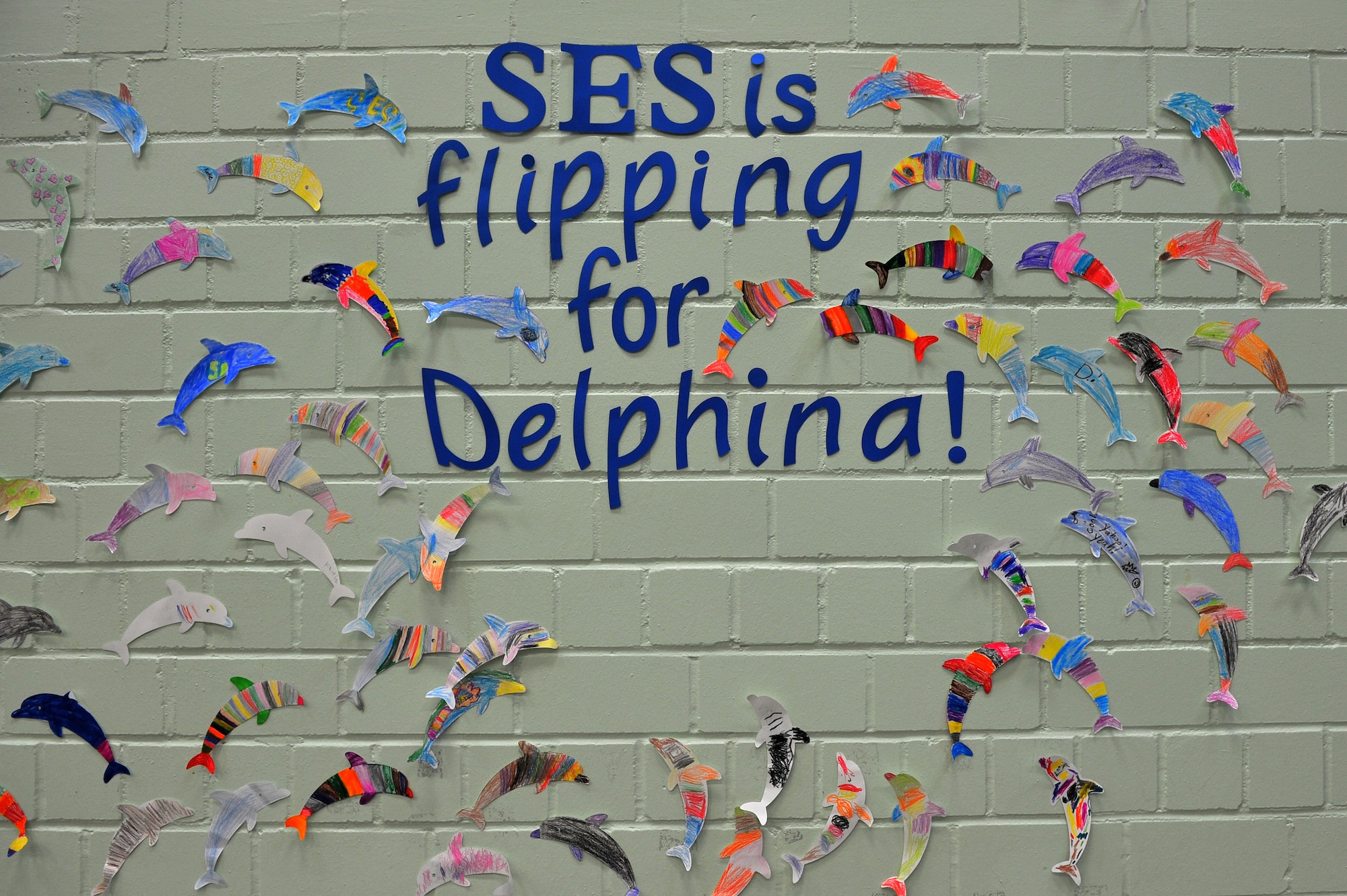 SPANGDAHLEM AIR BASE, Germany – Dolphin-shaped artwork, symbolizing donations, decorates the wall of the Spangdahlem Elementary School cafeteria here May 25. Students raised money from donations to adopt Delfina, a wild bottlenose dolphin, for one year through the World Wildlife Fund with help from the SES Parent Teacher Student Association. The WWF uses the donations to help protect and improve living conditions for wildlife species around the globe. (U.S. Air Force photo by Airman 1st Class Dillon Davis/Released)