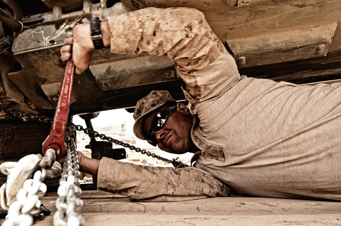 Cpl. Jason K. Fricke, assistant loadmaster, 3rd Platoon, Alpha Company, Combat Logistics Battalion 4, 1st Marine Logistics Group (Forward), tightens a set of chains holding down a 7-Ton medium tactical vehicle replacement May 29. The 7-Ton was damaged during Operation Branding Iron.