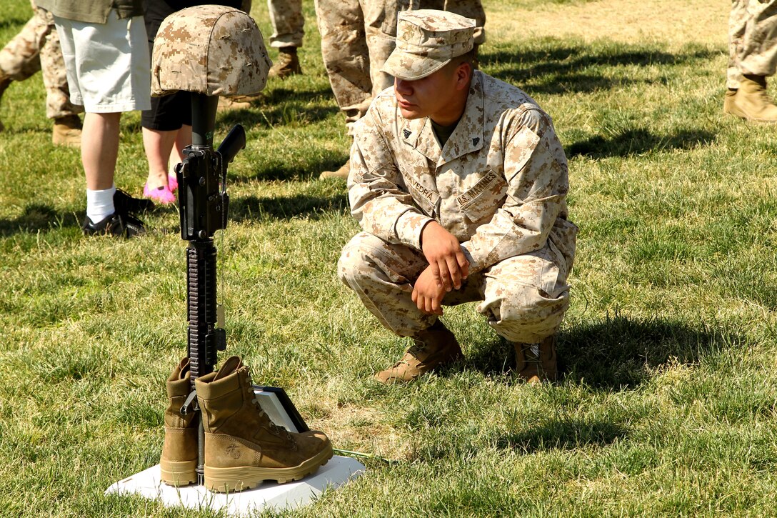 Cpl.  Miguel Saaver, combat engineer, 3rd Combat Engineer Battalion pays his respects to Cpl. Christopher Singer, one of the Marines honored at a Remembrance Ceremony at Lance Cpl Torrey L. Gray Field May 30, 2012. (Official USMC photo by Lance Cpl D. J. Wu)