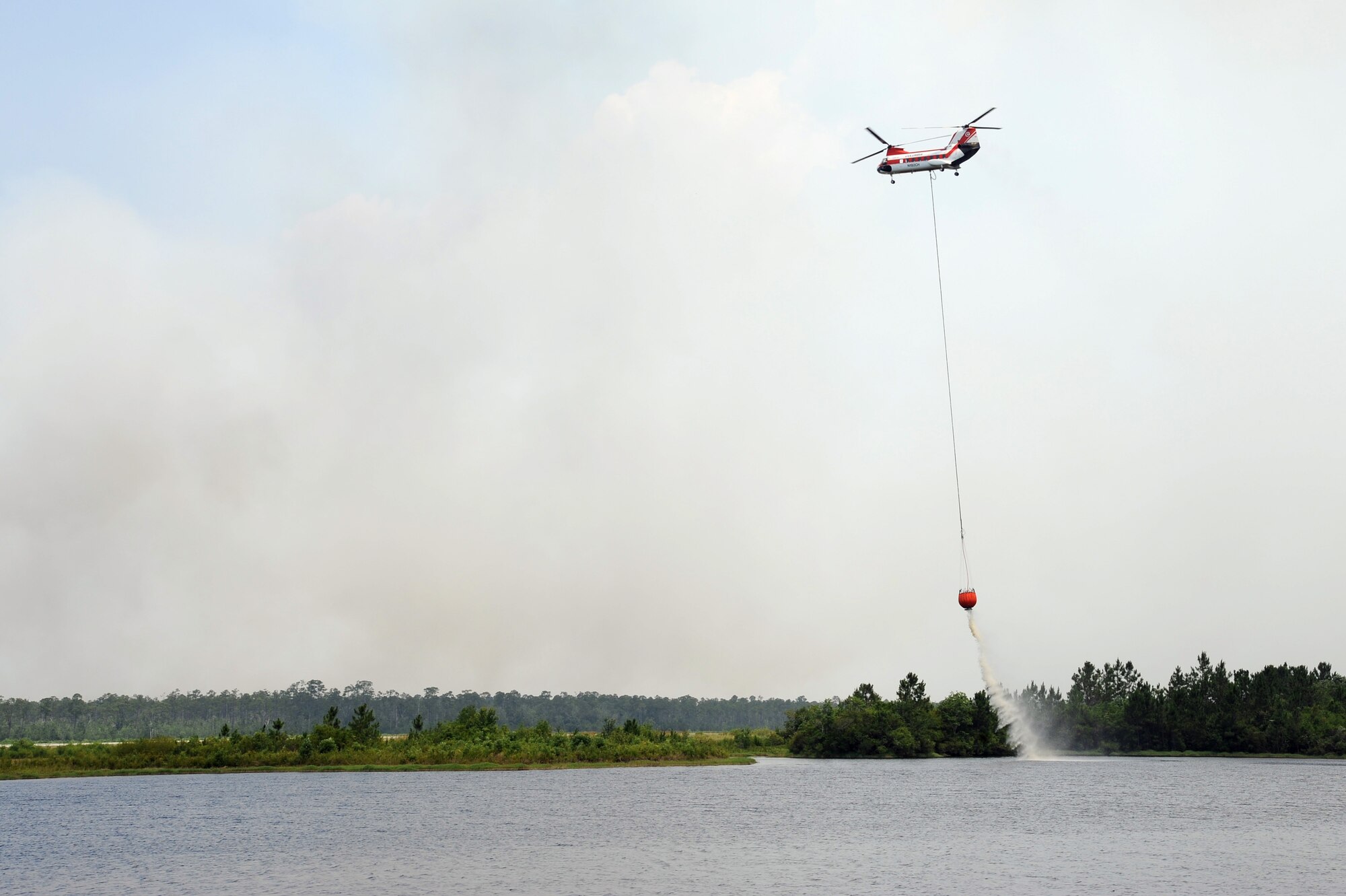 A CH-47 Chinook helicopter contracted by Jackson Guard gathers water using a Bambi Bucket from a pond on Gator Lakes golf course May 30, 2012 at Hurlburt Field, Fla. The helicopter is part efforts to douse the wildfire north of Hurlburt Field. (U.S. Air Force photo by Airman 1st Class Michelle Vickers)(Released)
