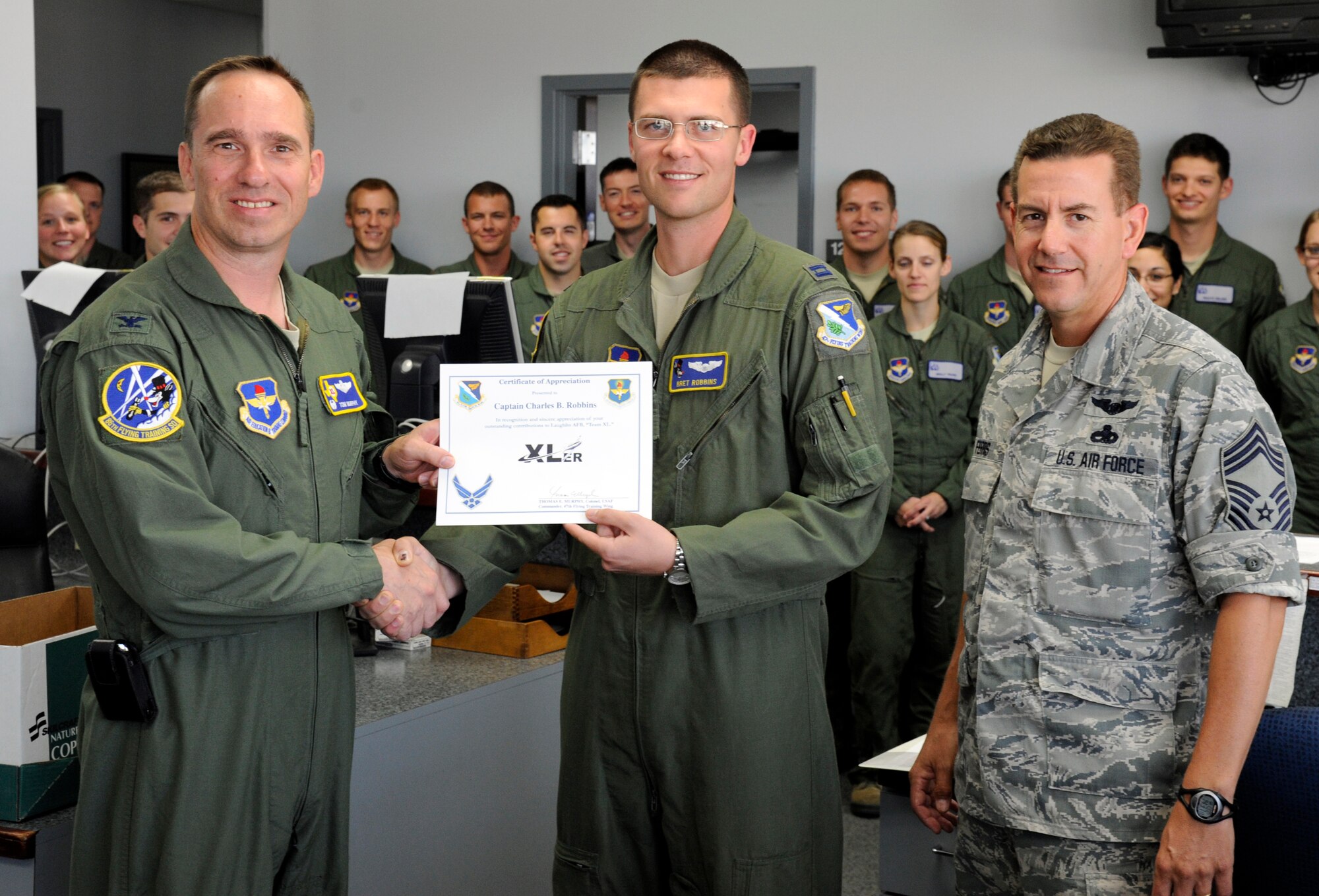 Capt. Charles Robbins, 86th Flying Training Squadron assistant flight commander, poses with Col. Tom Murphy, 47th Flying Training Wing commander, and Chief Master Sgt. Dean Ferris, 47th Operations Group superintendant, after being presented the XLer of the week award at Laughlin Air Force Base, Texas, May 23, 2012. The XLer is a weekly award chosen by wing leadership and given to those who consistently make outstanding contributions to Laughlin and their unit. (U.S. Air Force photo/Airman 1st Class Nathan Maysonet)