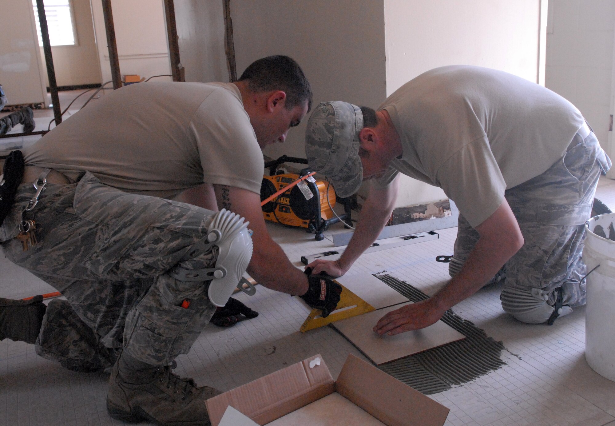 Senior Airman Leonard Thibodeaux (left) and Tech. Sgt. Jeffrey Bopp from the 647th Civil Engineer Squadron at Joint Base Pearl Harbor-Hickam, Hawaii, lay tile on the floor of a cabin at Bellows Air Force Station May 23 as part of the squadron's Prime BEEF exercise. Prime Base Engineer Emergency Force (BEEF) teams are rapidly deployable, specialized civil engineer units, that provide a full range of engineering support required to establish, operate, and maintain garrison and contingency airbases. (U.S. Air Force photo by 2nd Lt. Jessica Rowe)