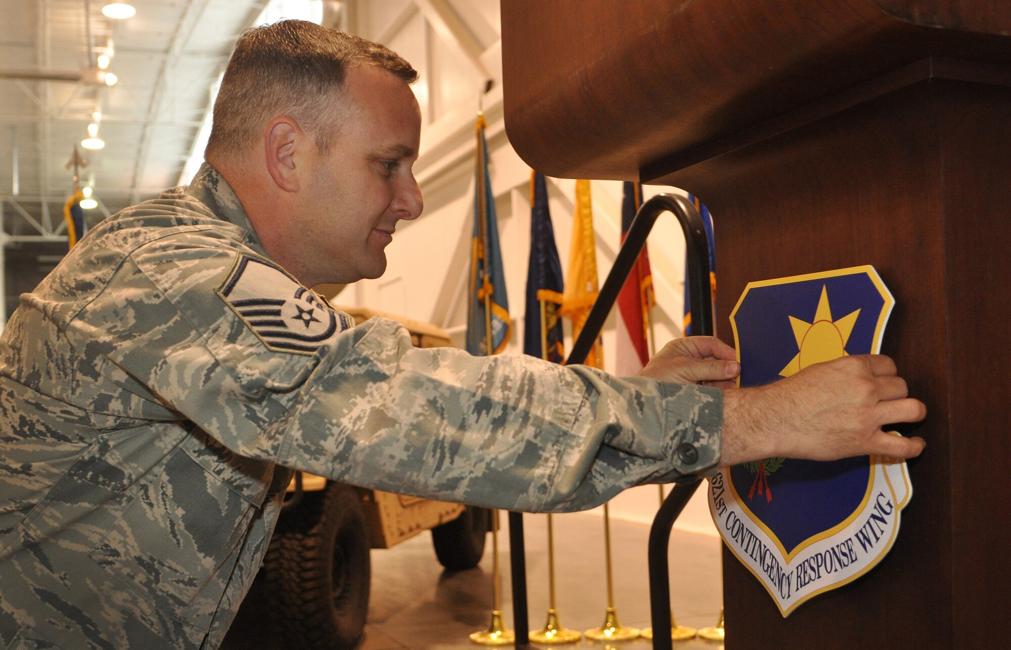 Master Sgt. Jeffrey Steere, assigned to the 573rd Global Support Squadron, attaches the 621st Contingency Response Wing Patch to the podium following the inactivation ceremony of the 615 CRW, May 29, 2012, at Travis Air Force Base, Calif. The 615 CRW ceased its operations as a sister wing, ending seven years of mobility excellence. The inactivation ceremony also included the transfer of command of the two contingency response groups and one contingency operations group to the 621st Contingency Response Wing, headquartered at Joint Base McGuire-Dix-Lakehurst, N.J. (U.S. Air Force Photo / Master Sgt. Stan Parker)