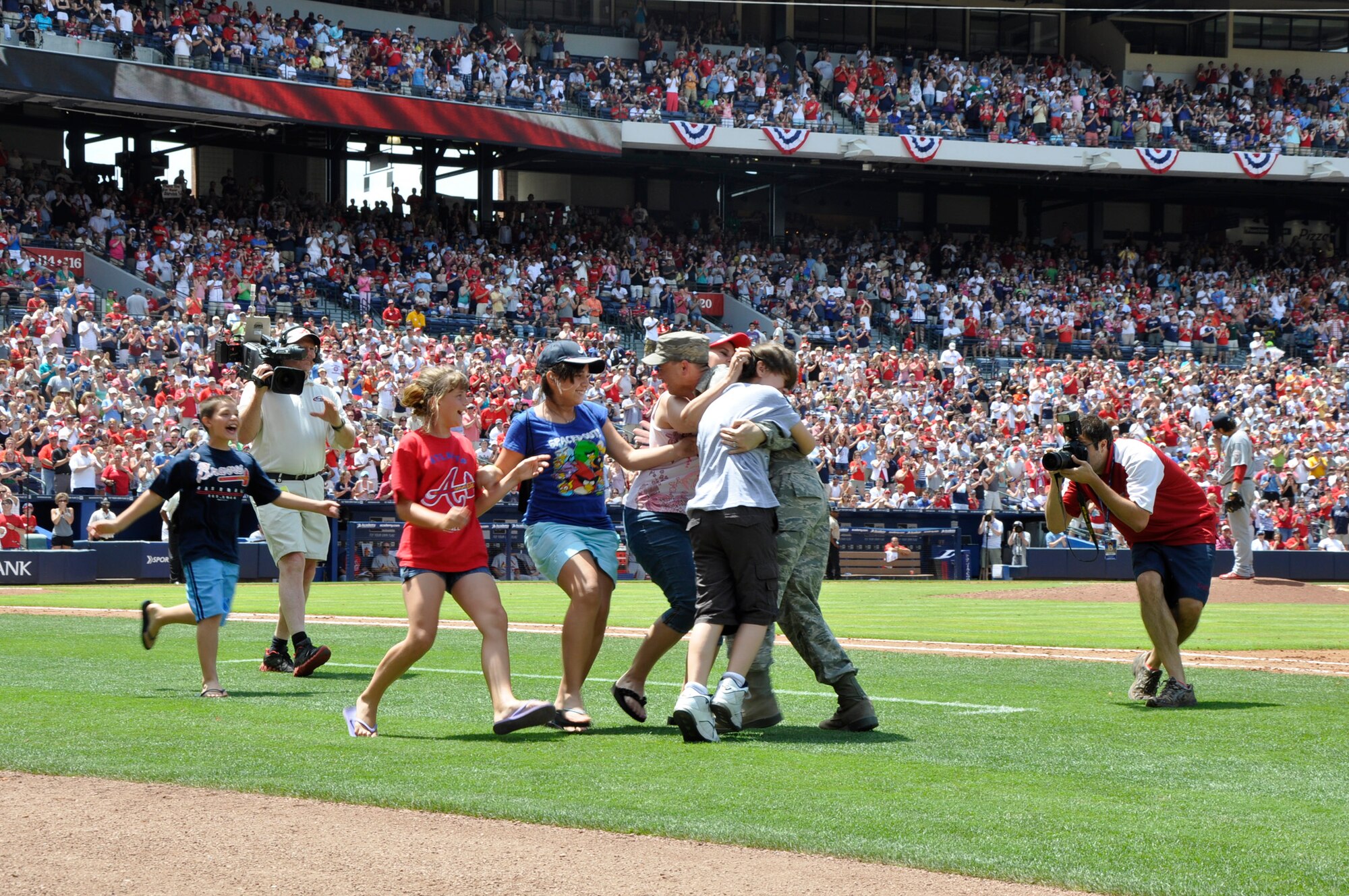 Master Sgt. David Sims and his family embrace during a surprise homecoming May 28, 2012, at Turner Field in Atlanta. Sims’ family attended the Atlanta Braves game and was called onto the field at the top of the fifth inning for a special video tribute from Sims, who they thought was still in Afghanistan. Sims is assigned to Headquarters Air Force Reserve Command's Communications Directorate at Robins Air Force Base, Ga. (Defense Department/Photo by Jessica Blanton)