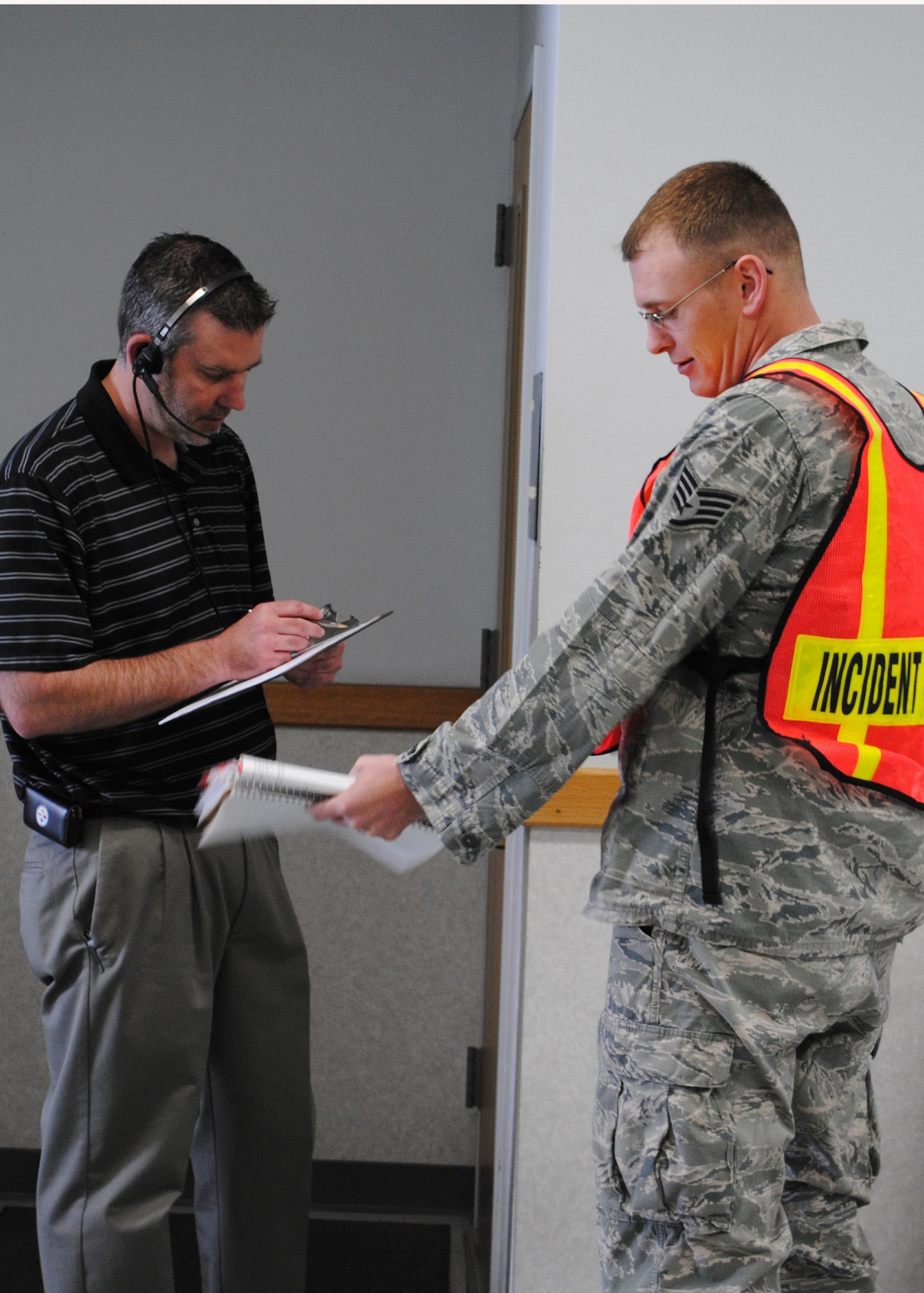 Matthew Simmons, Fire Officer instructor, left, goes over information pertaining to a fire scenario May 21 with Staff Sgt. Jason Haugen, 5th Civil Engineer Squadron firefighter; Minot AFB, N.D.; who was acting as the scenario's incident commander. Each student in the Fire Officer II class had a chance to act as the incident commander for a fire scenario. (U.S. Air Force photo/Airman 1st Class Cortney Paxton)