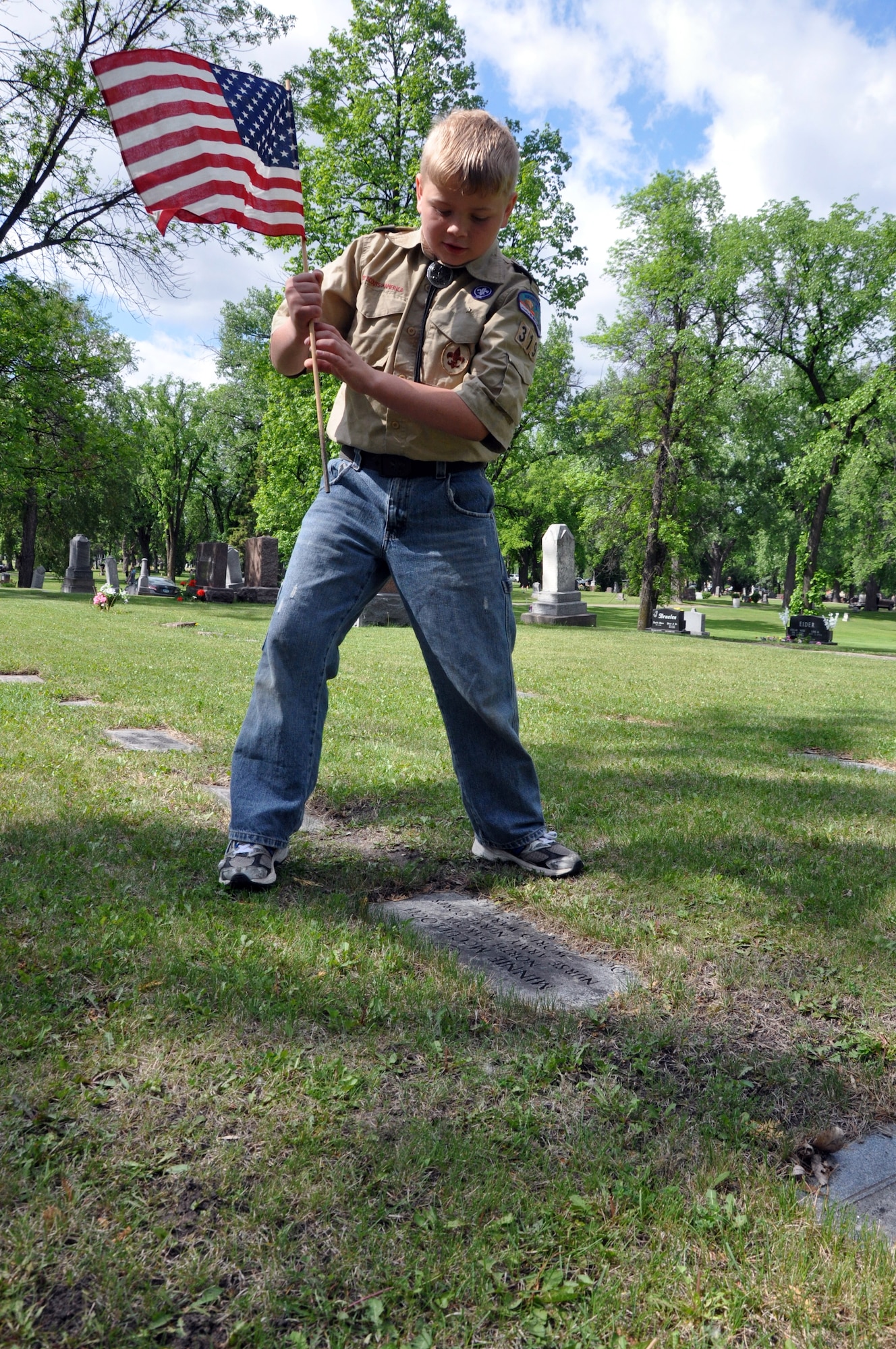 Caleb Thieme, 10, of Grand Forks Air Force Base, N.D., prepares to place a U.S. flag on a grave at Memorial Park Cemetery in Grand Forks city on May 25, 2012, in advance of Memorial Day. Thieme, a member of the base’s Boy Scout Troop 319, was among about 225 base volunteers who helped with the project, co-sponsored by the Veterans of Foreign Wars and Disabled American Veterans organizations. (U.S. Air Force photo/Tim Flack)