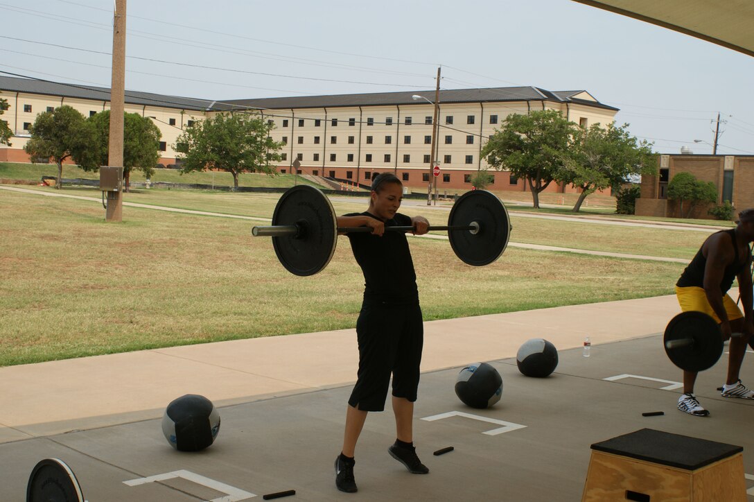 Carly Martinez, spouse of Tech. Sgt. Jaime Martinez of the 361st Training Squadron, pumps iron during the "Combat Fit" workout outside the Pitsenbarger Fitness Center May 24, 2012.  Martinez has seen dramatic improvement in her overall fitness levels since committing to the "Combat Fit" program five months ago. (U.S. Air Force photo/2Lt Jerred Moon)