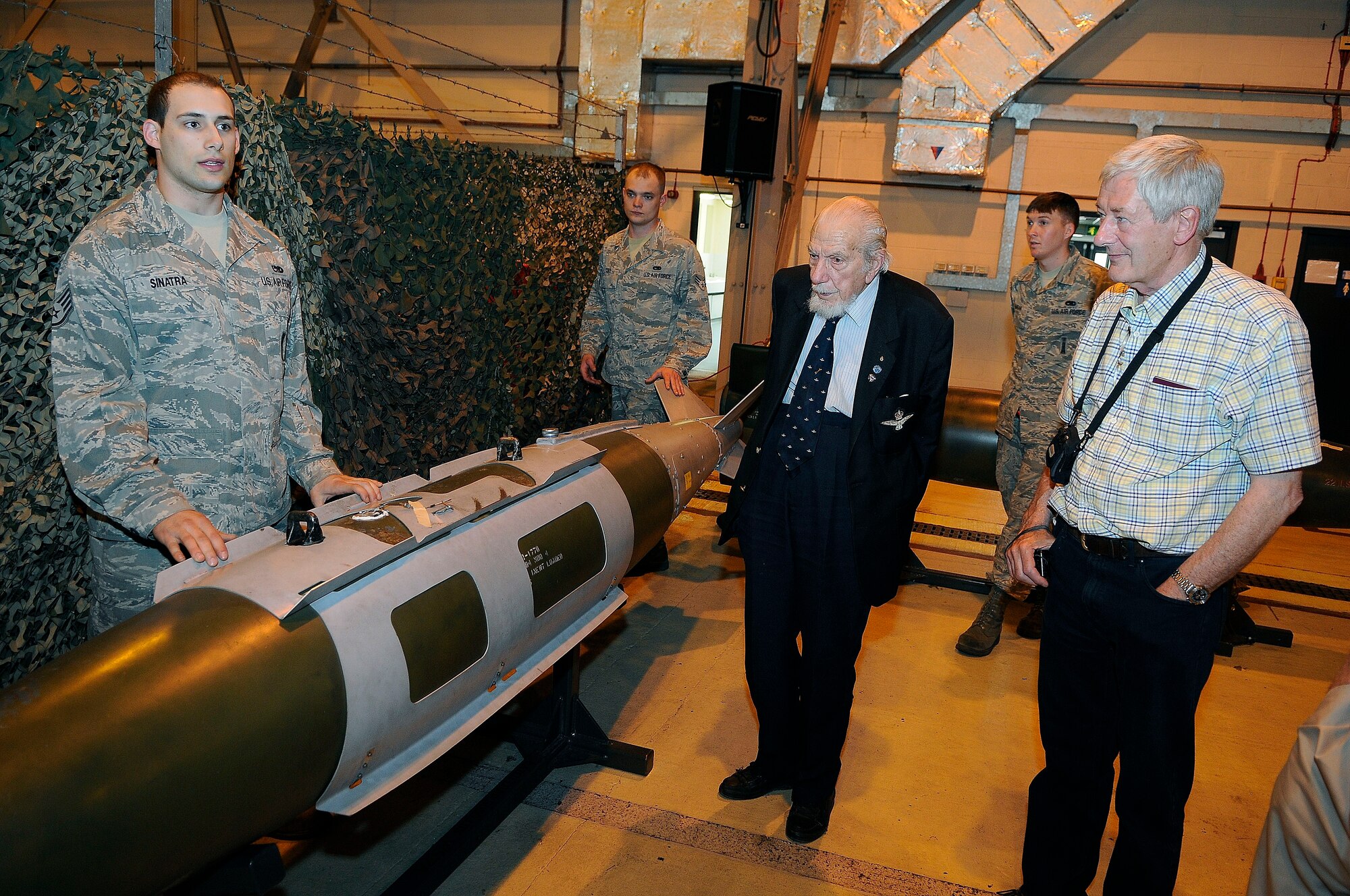 ROYAL AIR FORCE LAKENHEATH, England - Staff Sgt. Anthony Sinatra, (left) 48th Maintenance Operations Squadron weapons standardization lead crew member, gives a briefing about different munitions to Kenneth Wallis, retired RAF wing commander (middle), and the RAF Halton Ex Apprentices group during a base tour of Hangar 6 May 24, 2012. Wallis completed 24 missions over Europe as a pilot of Wellington bombers during WWII and flew the Convair B-36 Peacemaker under General Curtis E. LeMay in 1956. (U.S. Air Force photo by Staff Sgt. Connor Estes)