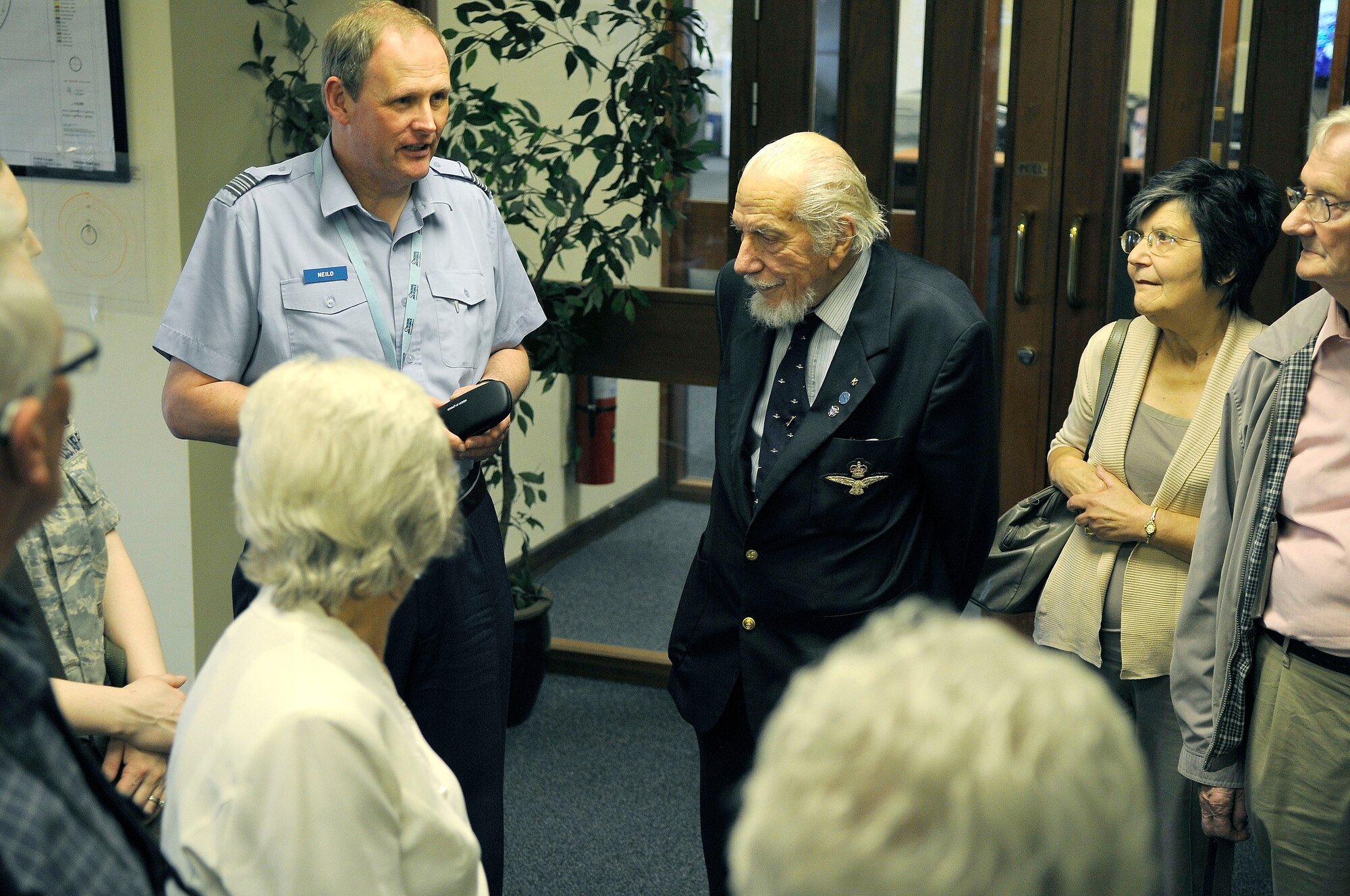 ROYAL AIR FORCE LAKENHEATH, England - RAF Squadron Leader Jeremy Neild (left), gives a briefing about flying operations to Kenneth Wallis, retired RAF wing commander (middle) and the RAF Halton Ex Apprentices group during a base tour at the airfield management office May 24, 2012. Wallis has been involved in movies such as ?You Only Live Twice,? where he played James Bond?s double while flying an autogyro. (U.S. Air Force photo by Staff Sgt. Connor Estes)