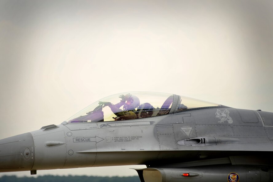A U.S. Air Force F-16 Fighting Falcon fighter pilot assigned to the 79th Fighter Squadron "Tigers" uses hand gestures to represent his squadron while taxiing into formation to participate in an elephant walk during an Operational Readiness Exercise, May 22, 2012, Shaw Air Force Base, S.C. An elephant walk occurs when aircraft taxies down the runway in large numbers, which represents the ability to generate a large number of aircraft needing to take off rapidly for a military response. (U.S. Air Force photo by Senior Airman Kenny Holston/Released)


