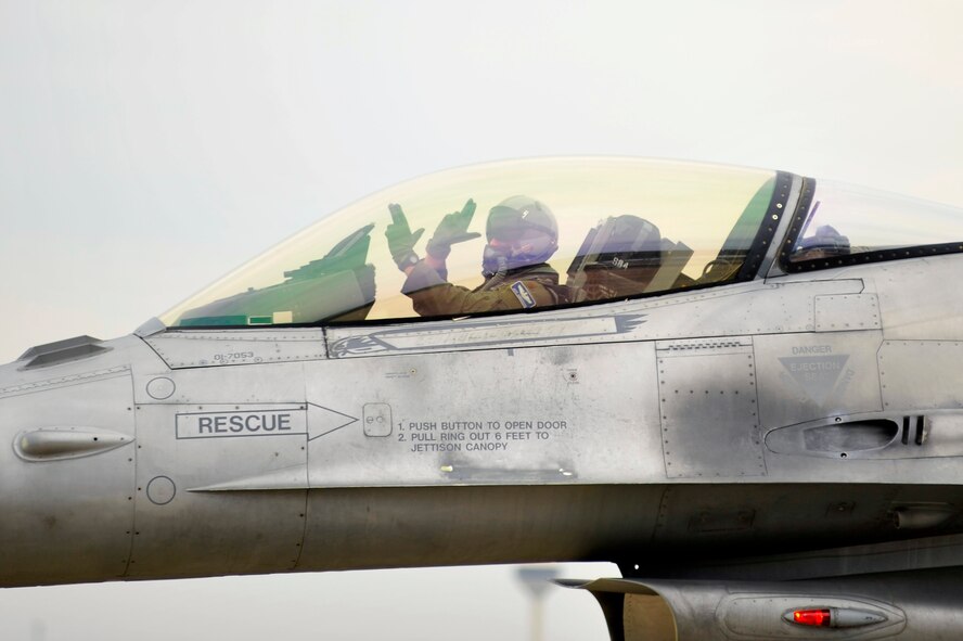 A U.S. Air Force F-16 Fighting Falcon fighter pilot assigned to the 55th Fighter Squadron "Shooters" uses hand gestures to represent his squadron while taxiing into formation to participate in an elephant walk during an Operational Readiness Exercise, May 22, 2012, Shaw Air Force Base, S.C. An elephant walk occurs when aircraft taxies down the runway in large numbers, which represents the ability to generate a large number of aircraft needing to take off rapidly for a military response. (U.S. Air Force photo by Senior Airman Kenny Holston/Released)


