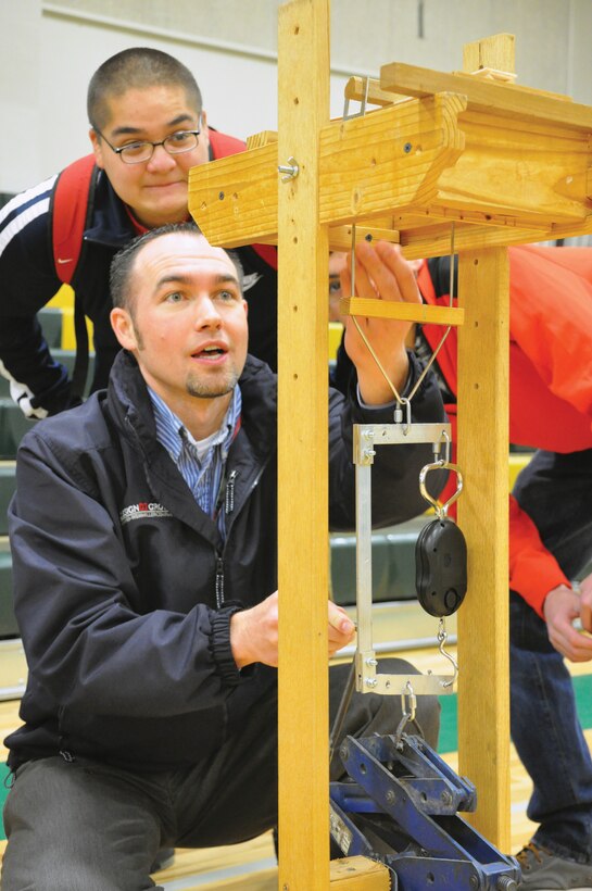 Jesus Lara watches as District Civil Engineer Michael Franssen tests his balsa-wood bridge at DeSales High School Walla Walla, Wash. Feb. 23.