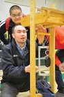 Jesus Lara watches as District Civil Engineer Michael Franssen tests his balsa-wood bridge at DeSales High School Walla Walla, Wash. Feb. 23.