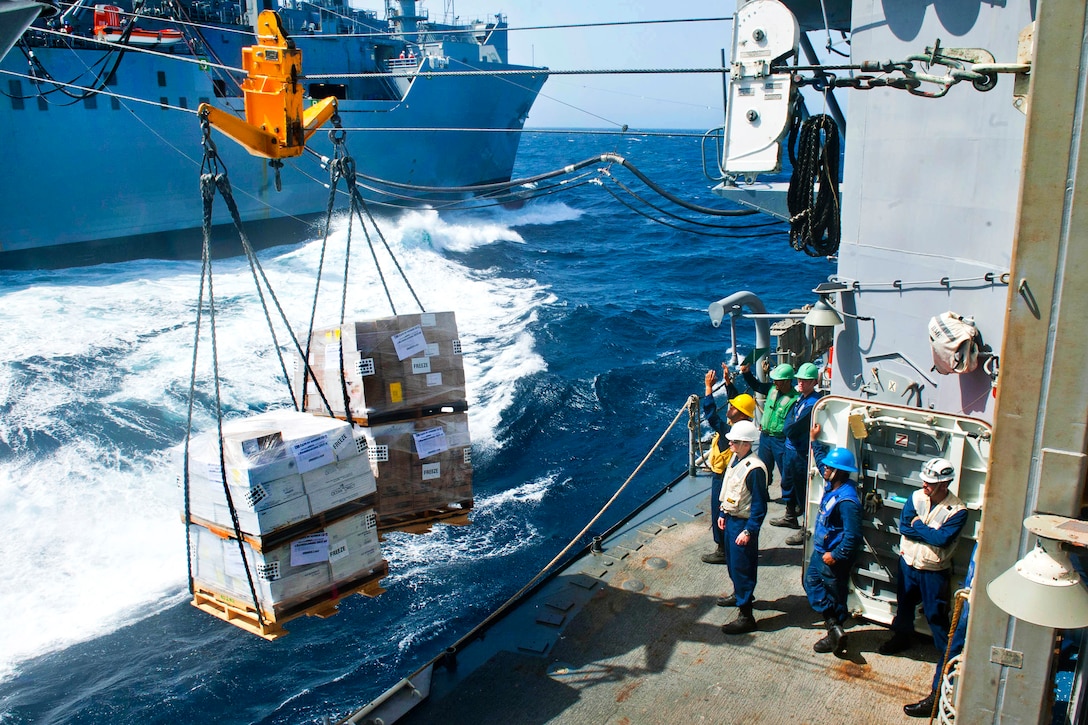U.S. Navy Petty Officer 3rd Class Josue Ortiz, center, uses hand signals to guide supplies aboard the guided-missile cruiser USS Cape St. George from the Military Sealift Command dry cargo and ammunition ship USNS Charles Drew during a replenishment in the Arabian Sea, May 24, 2012. Ortiz is a boatswain’s mate.