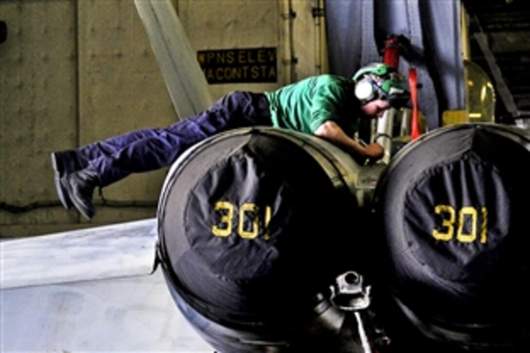 U.S. Navy Seaman Benjamin Huffman performs maintenance on an F/A-18C Hornet assigned to Strike Fighter Squadron 151 in the hangar bay of the aircraft carrier USS Abraham Lincoln under way in the Arabian Sea, May 24, 2012. Huffman is an aviation structural mechanic airman.