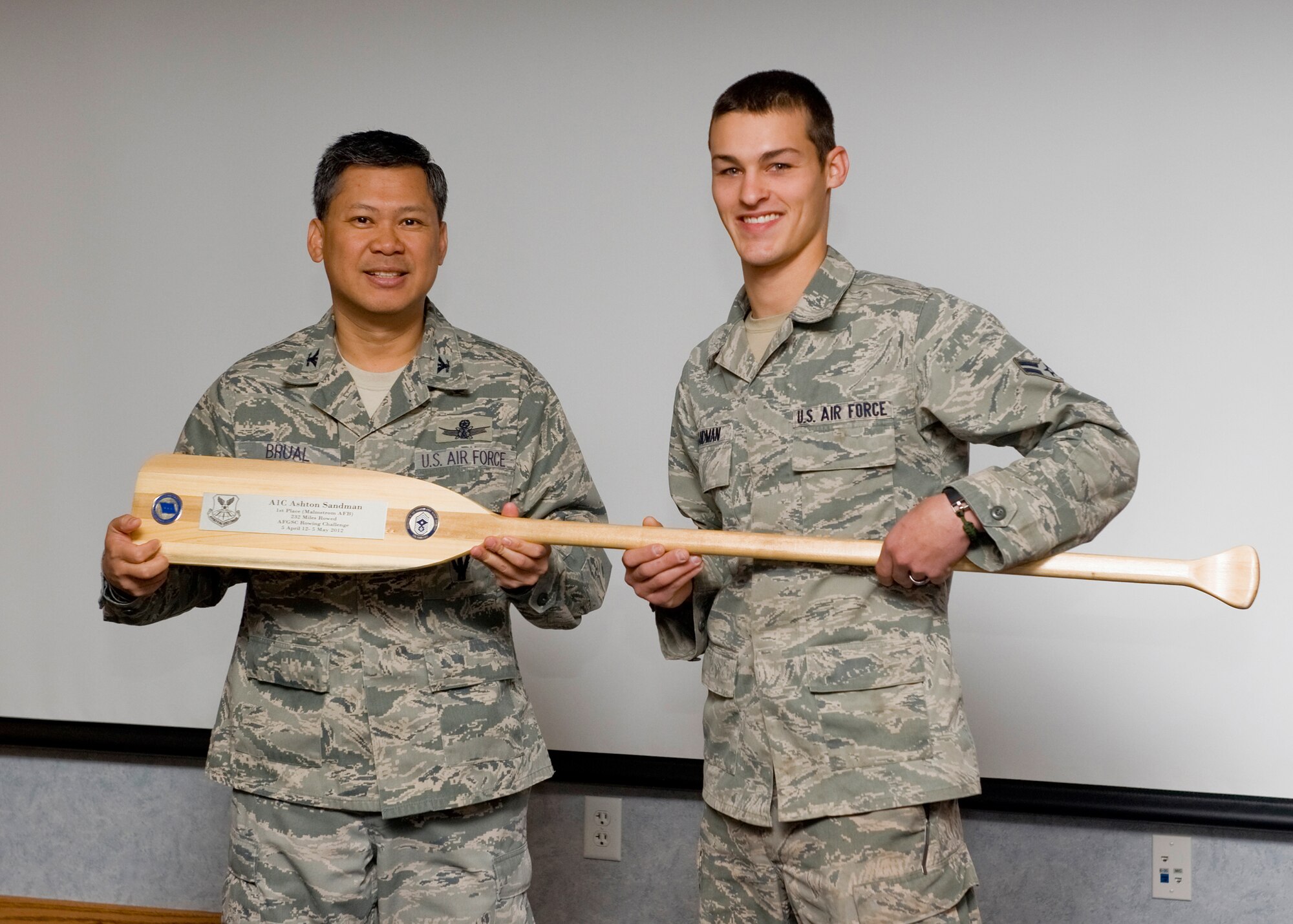 Col. H.B. Brual, 341st Missile Wing commander, presents Airman 1st Class Ashton Sandman, 819th RED HORSE Squadron pavement and equipment operator, with a trophy for being Malmstrom Air Force Base's top rower in the Air Force Global Strike Command Rowing Challenge May 30. Sandman also received a $400 travel voucher for his accomplishment. He rowed 232 miles cumulatively during the month-long challenge. (U.S. Air Force photo/Beau Wade)