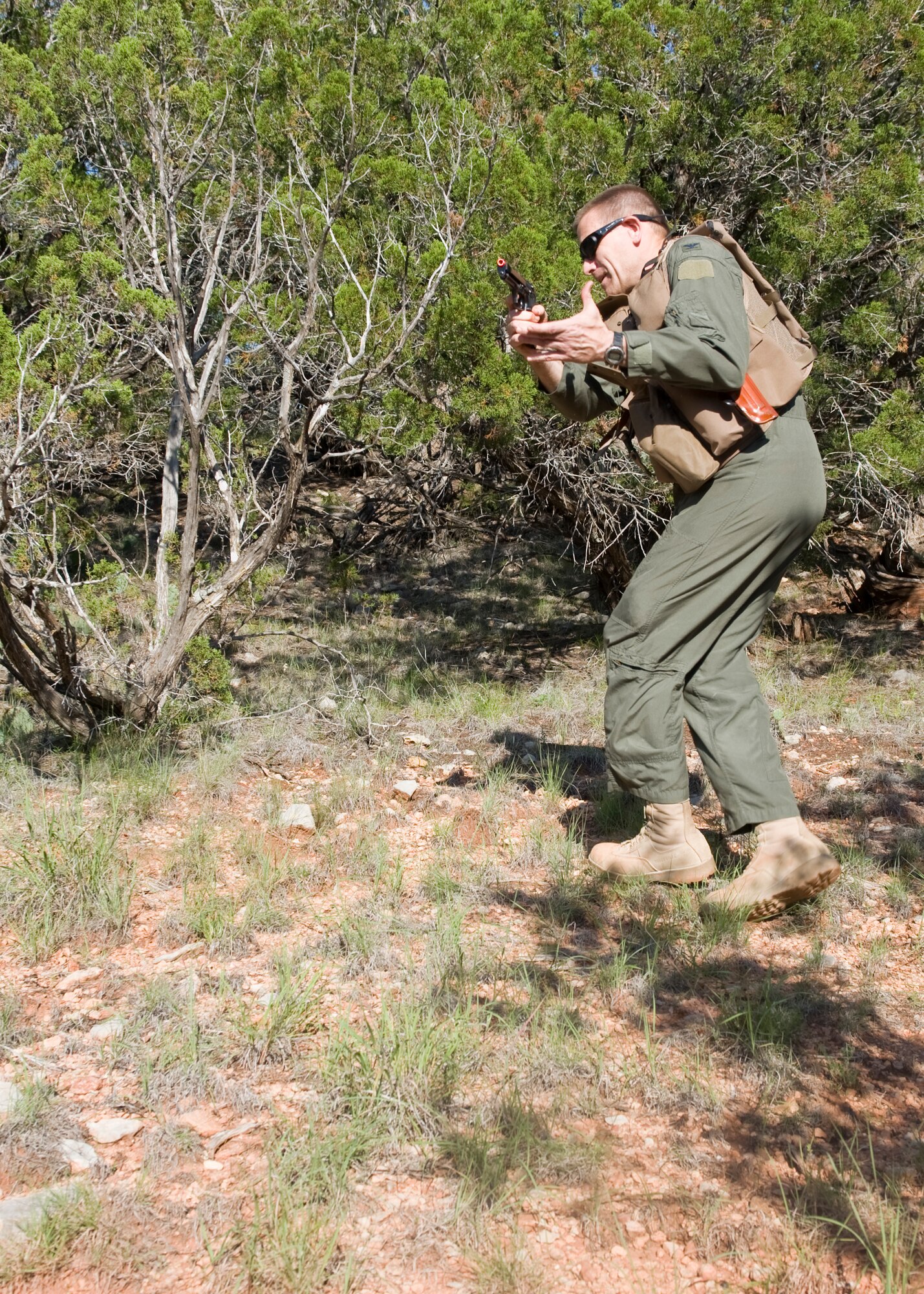 U.S. Air Force Col. Walter Ward, 317th Airlift Group commander, draws his firearm while retreating to cover in an active-shooter exercise during navigation and personnel recovery training May 16, 2012, at Lake Abilene in Abilene, Texas. During the navigation and personnel recovery training, airmen navigate difficult terrain to a rally point while avoiding capture. (U.S. Air Force photo by Airman 1st Class Peter Thompson/ Released)