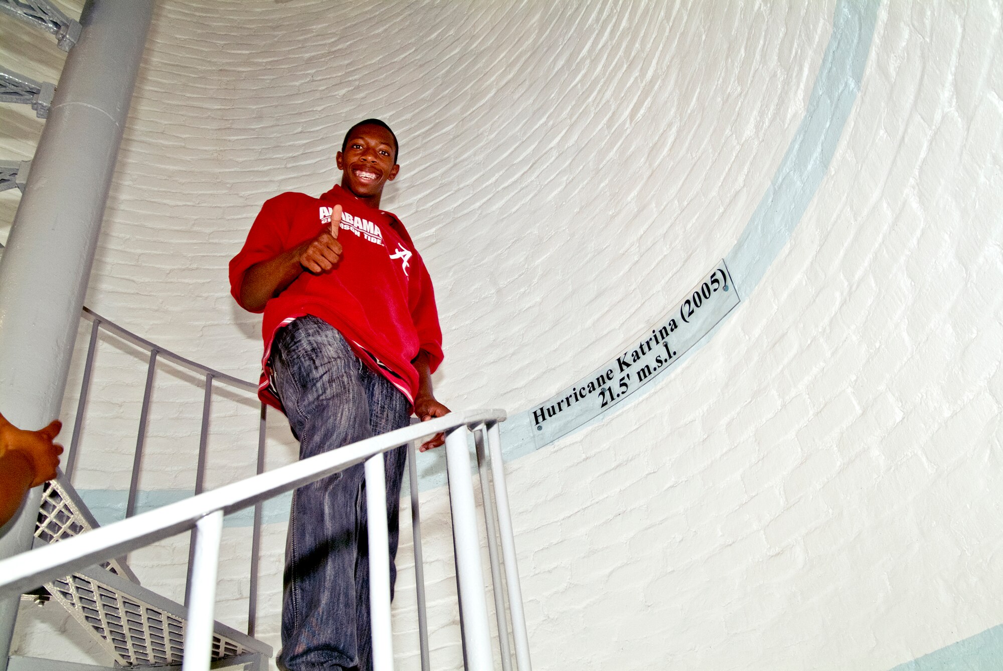 Charles Moore Jr. gives the thumbs up at the stripe marking the height of the Hurricane Katrina flood surge in the Biloxi Lighthouse, Miss. Moore is a youth center teen group member who volunteered to help take the Keesler Youth Center group on a tour of the Biloxi Lighthouse.  Charles is the son of Charles Moore, 403rd Aircraft Maintenance Squadron, Keesler Air Force Base, Miss.  (U.S. Air Force photo by Herb Welch)