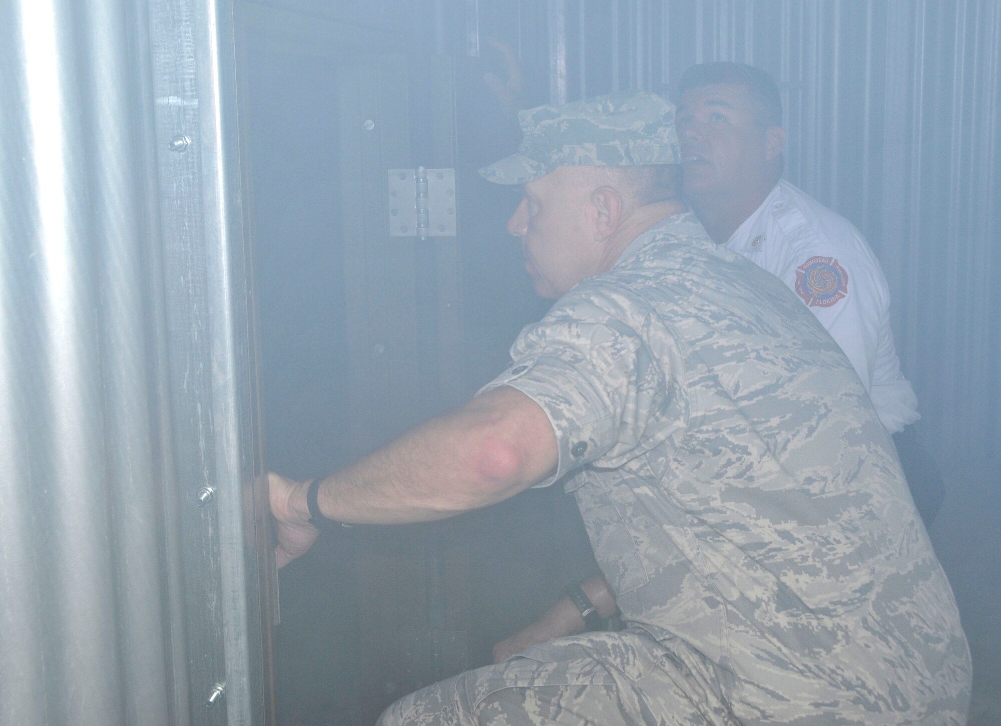 As simulated smoke fills the area, Col. Elwin A. Rozyskie Jr., 482nd Mission Support Group commander, receives a tour of the 482nd Fire Department’s new Class A burn facility from Chief Raymond Bradshaw, 482nd Fire Department, at Homestead Air Reserve Base, May 30. The burn facility is used for live fire, search and rescue, technical rescue training, as well as several other functions. (U.S. Air Force photo/Ross Tweten)
