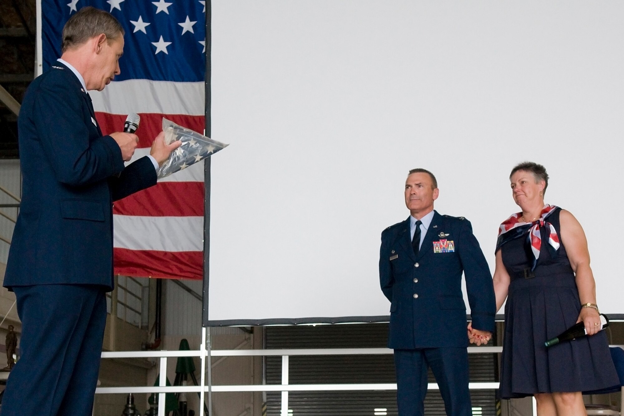 GRISSOM AIR RESERVE BASE, Ind. -- Retired Col. Ronald Farris explains to Col. William T. "Tim" Cahoon and his wife Vicki the story of the flag he holds before presenting it to Cahoon during his retirement ceremony here May 20. The flag flew over the 451st Air Expeditionary Group headquarters at Kandahar Airfield, Afghanistan, a unit that both Cahoon and Farris commanded. (U.S. Air Force photo/Senior Airman Jami K. Lancette)
