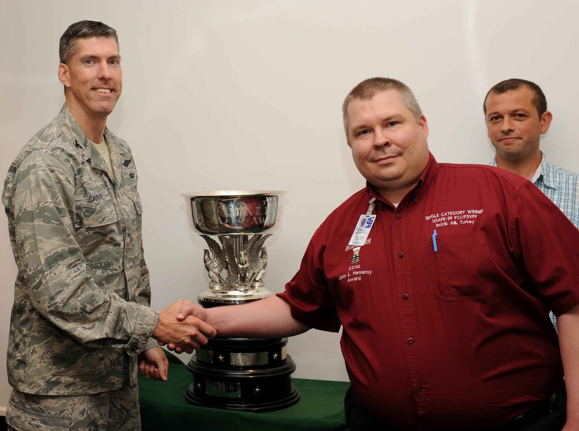 Col. Chris Craige, 39th Air Base Wing commander, awards Andrew Pastula, Sultan’s Inn Dining Facility manager, and Ahmet Irgit, Sultan’s Inn Dining Facility administration specialist, left to right, the 2012 John L. Hennessy Award, Single Unit Category, May 31, 2012, at Incirlik Air Base, Turkey. This is the second time in three years the Sultan's Inn staff received the Air Force-level award. The award program was adopted in 1956 to promote food service competition, and inspire better management and command support of food service. (U.S. Air Force photo by Senior Airman Jarvie Z. Wallace/Released)  