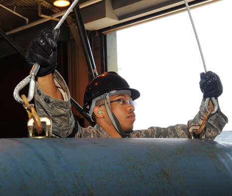 U.S. Air Force Senior Airman Willie Bivins, 35th Maintenance Squadron conventional maintenance crew member, hooks wire slings to suspension lugs attached to a BDU-50 prior to moving it at Misawa Air Base, Japan, May 31, 2012. The BDU-50 is a 2,000 pound training device. (U.S. Air Force photo by Airman Kenna Jackson/Released)